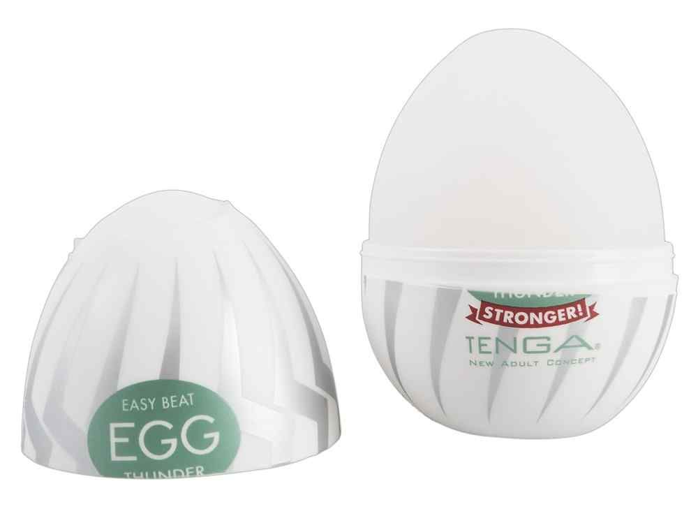 Zwei Teile eines weißen, eiförmigen Produkts mit grauen Streifen. Grünes Etikett mit "EGG THUNDER STRONGER!" und "TENGA".