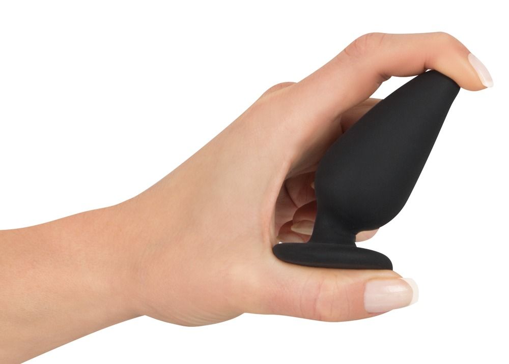 Schwarzer Analplug mit Standfuß, gehalten in einer Hand. Kegelförmiger Aufsatz, runder Fuß.