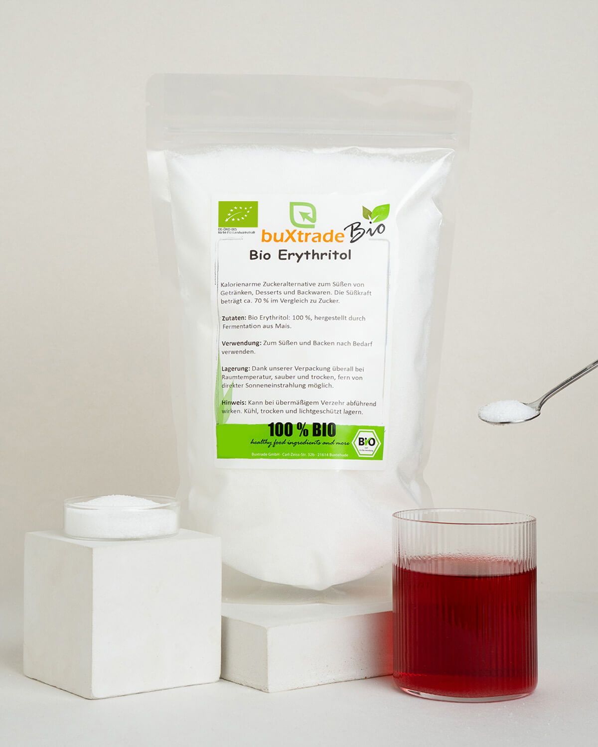 buXtrade Bio Erythritol bag with a spoon and glass of red liquid.