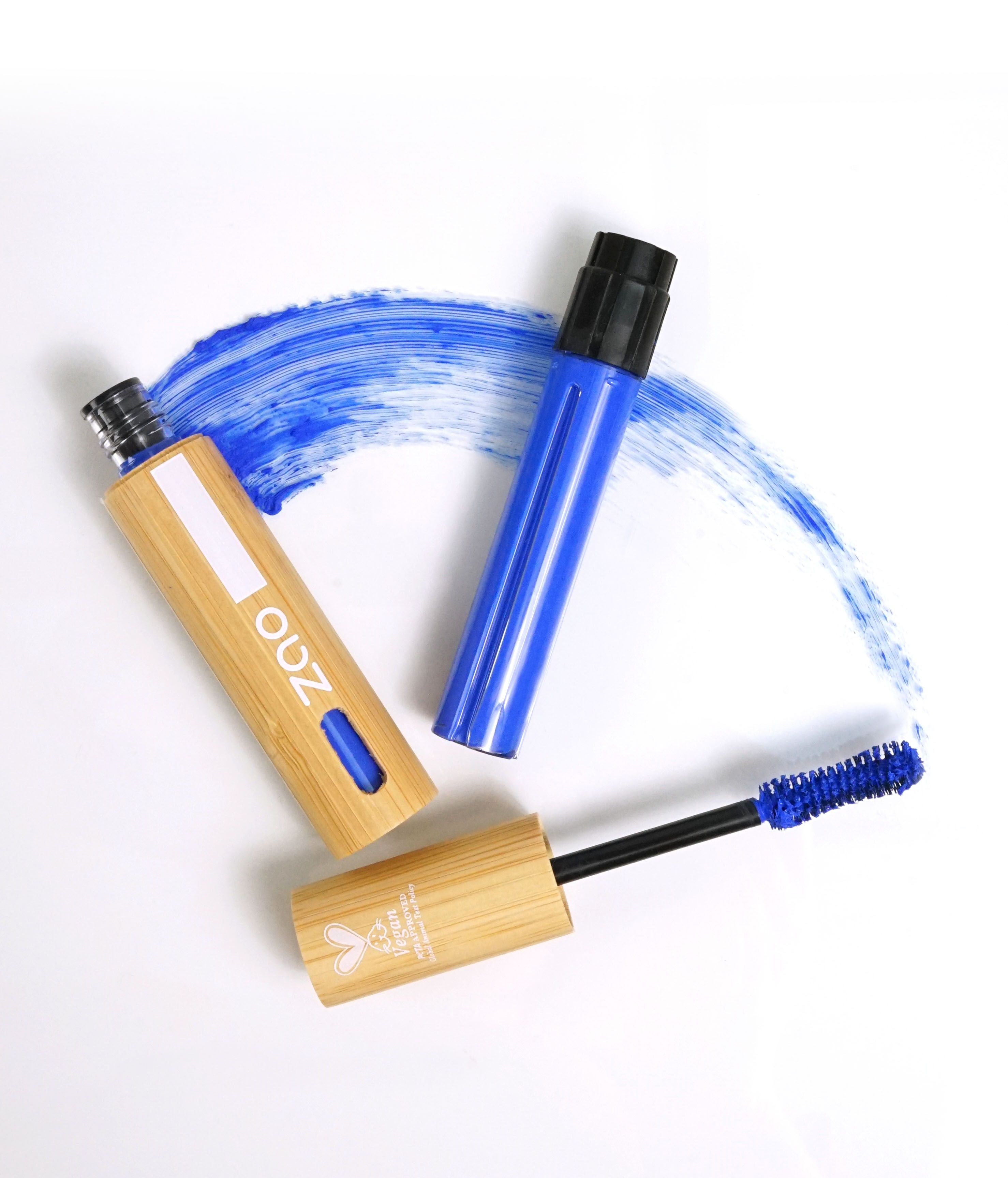 Zwei Mascara-Tuben aus Bambus, blau und schwarz. Ein Mascara-Applikator mit blauer Bürste. Vegan-Logo. Blauer Farbfleck.