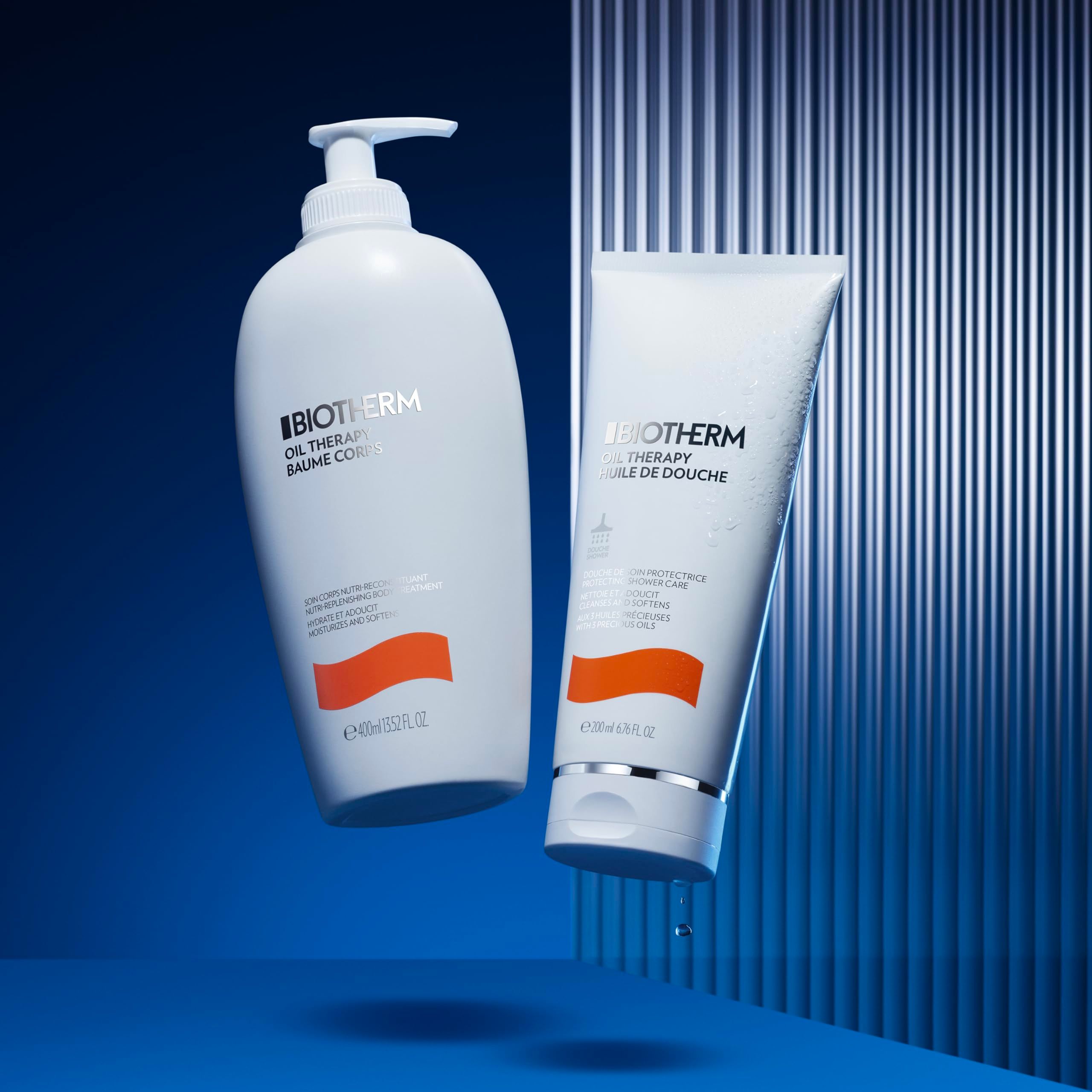 BIOTHERM Oil Therapy Baume Corps Flasche vor strukturiertem Glas und einem Ast mit Früchten.