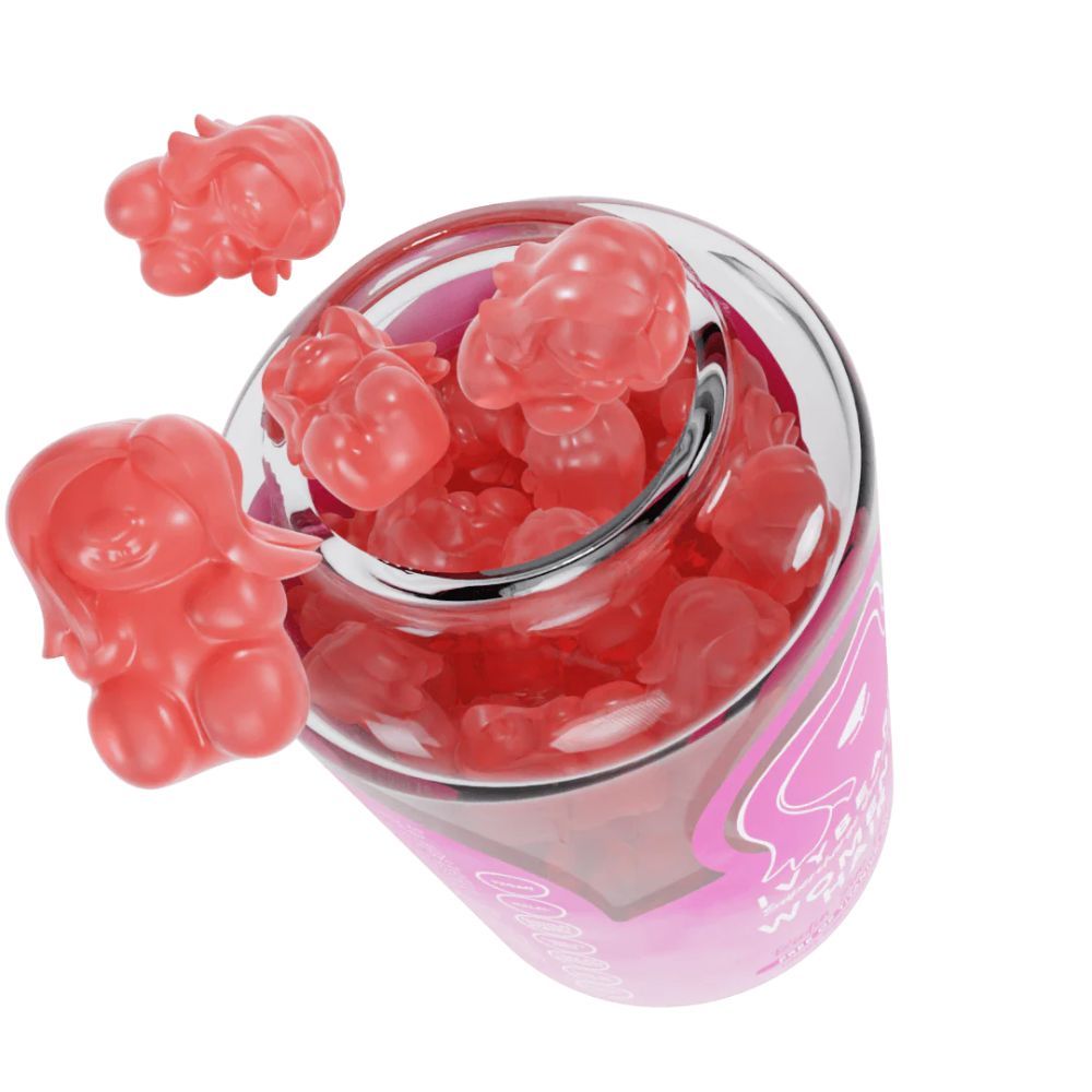 Glas mit pinkfarbenen Gummibärchen. Einige Gummibärchen liegen außerhalb des Glases. Blick von oben.