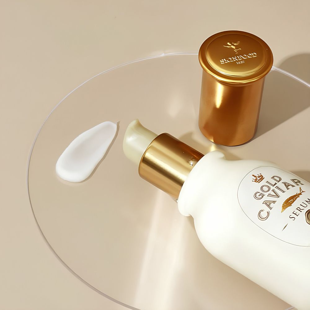 Serumflasche und Deckel auf Glasplatte. Klecks Serum daneben. Goldener Deckel. Marke: SKINFOOD.