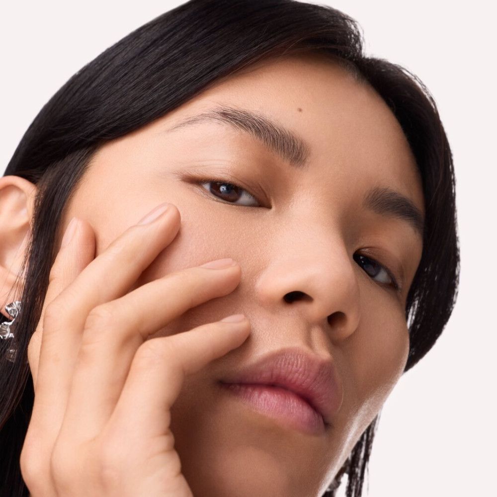 Nahaufnahme einer Person, die ihre Wange berührt. Fokus auf Augenbrauen und Haut. Natürliches Licht.