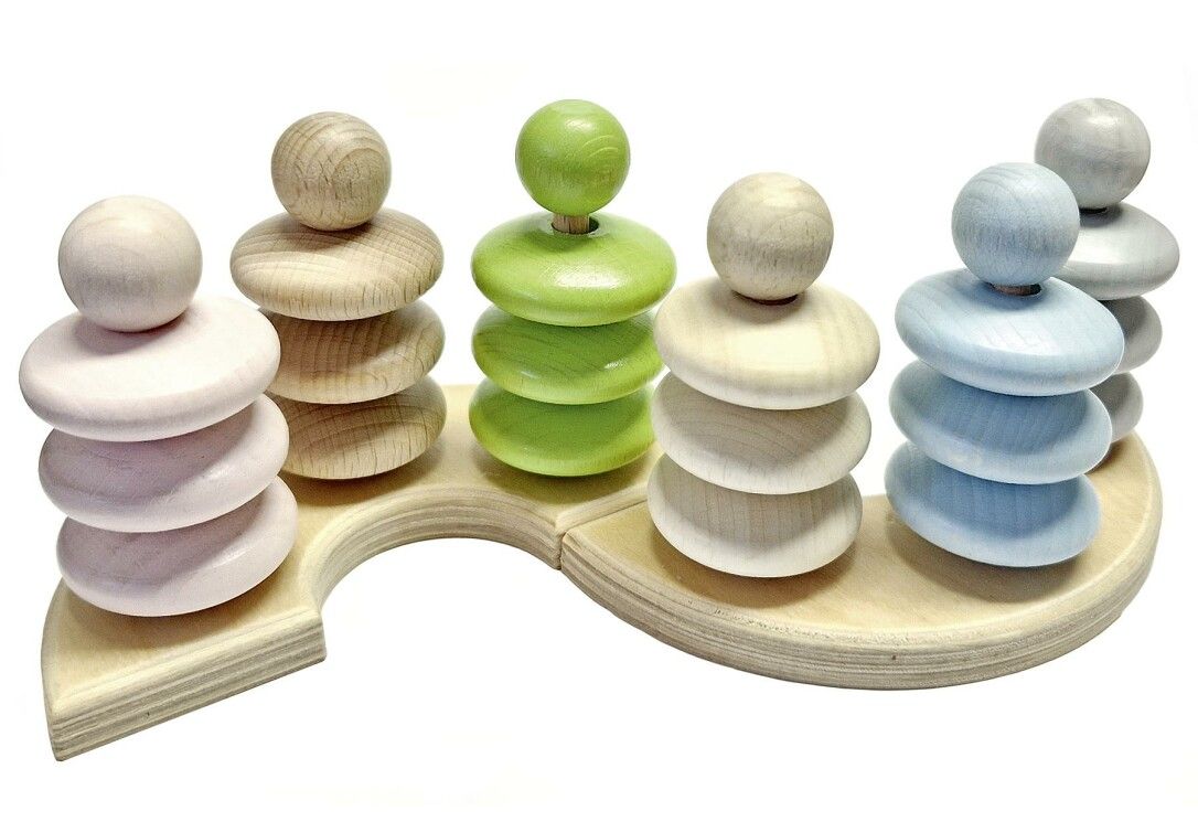 Holzspielzeug mit sechs Türmen in Pastellfarben auf einer geschwungenen Holzbasis. Jeder Turm hat Ringe und eine Kugel.