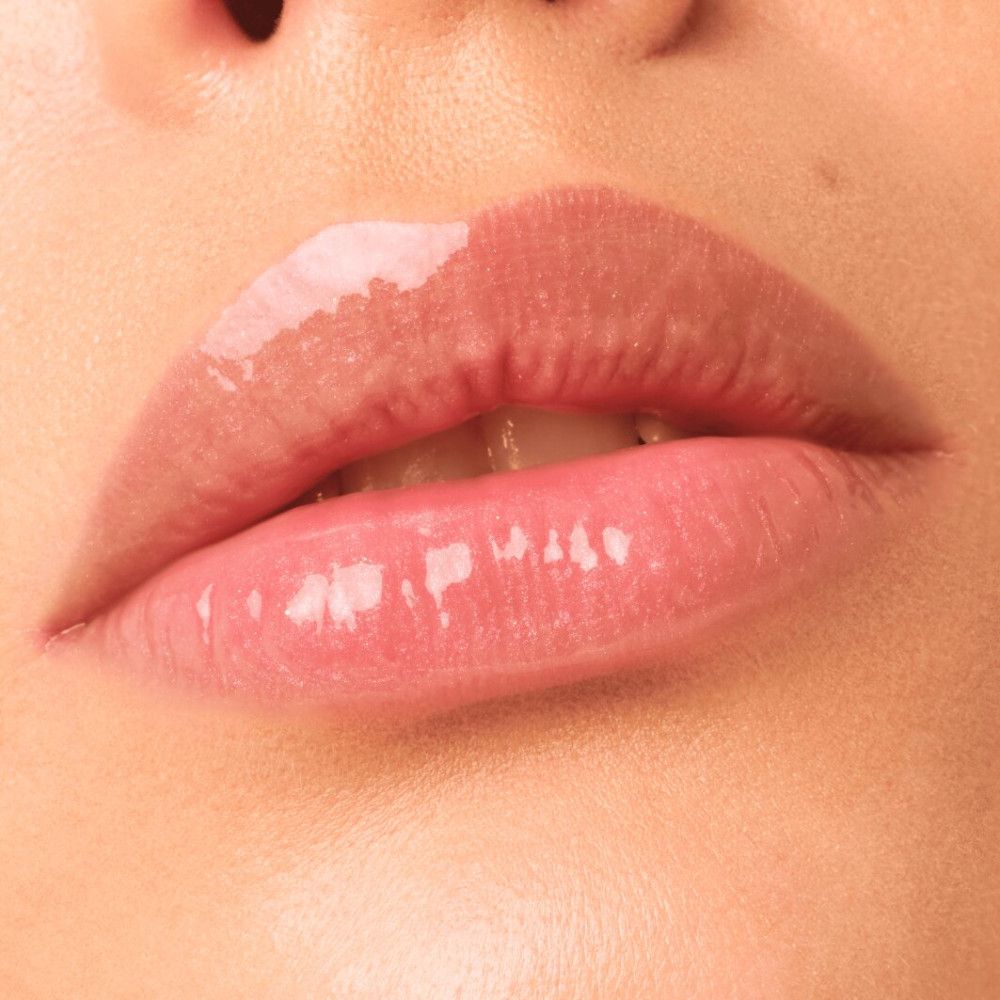 Nahaufnahme von Lippen, die mit Lipgloss bedeckt sind. Die Lippen sind glänzend und rosa getönt.