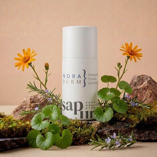 Weiße Spenderflasche mit 'Nora Derm' und 'SAPURA' Logo, umgeben von Moos, Steinen und gelben Blumen.