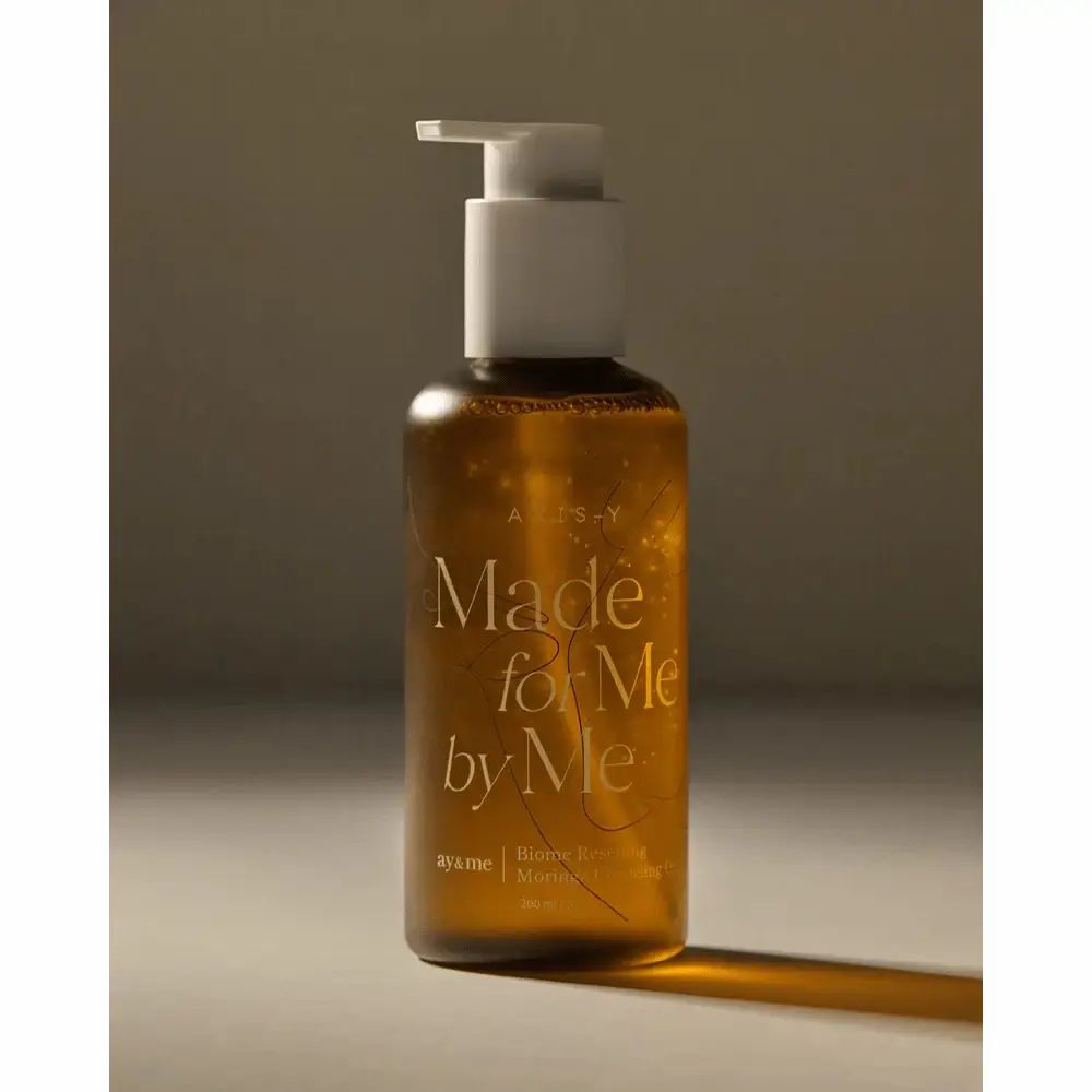 Braune Flasche mit weißem Pumpkopf. Aufschrift: AXIS-Y, Made for Me by Me, Biome Resetting Moringa Cleansing Oil.