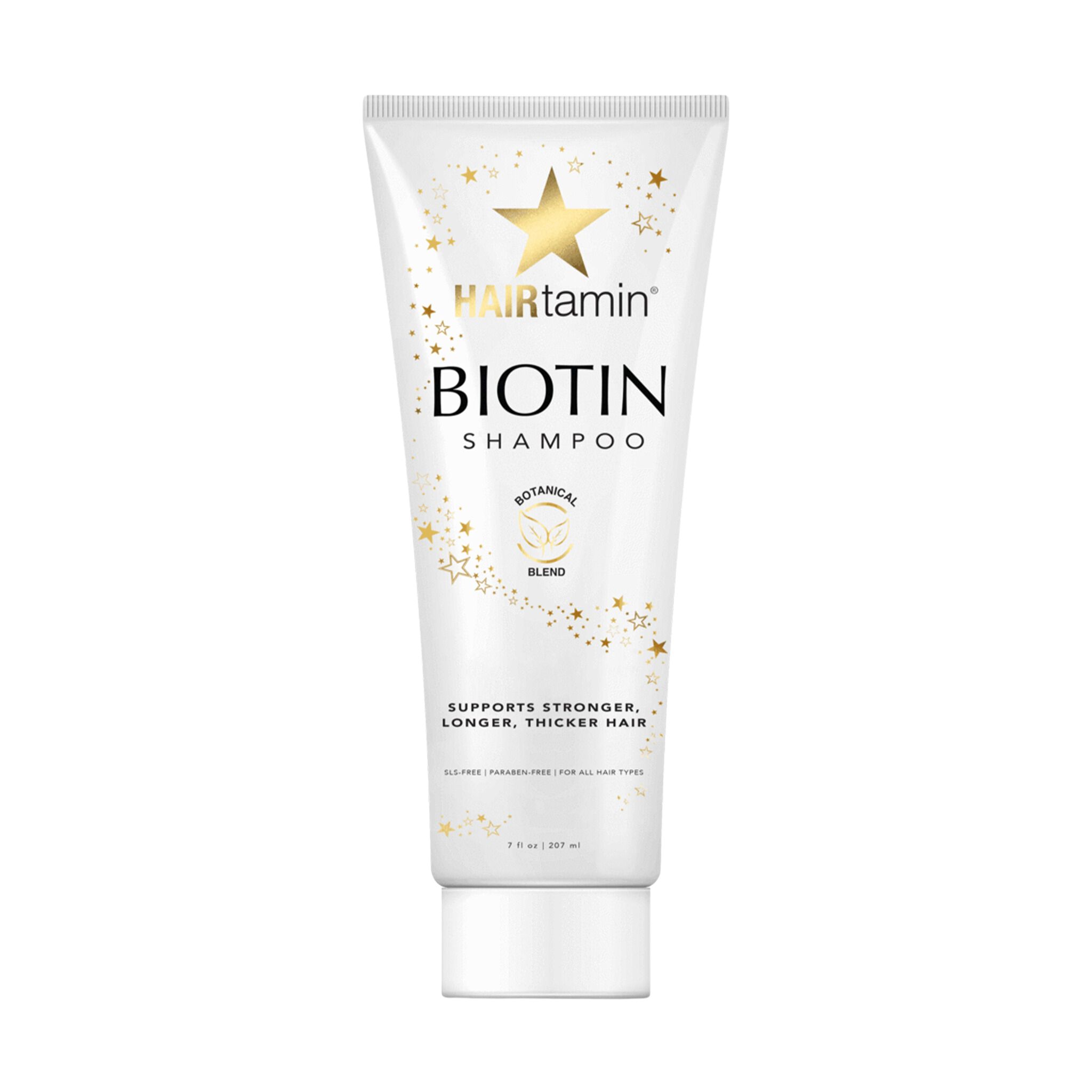 Weiße Tube mit "HAIRtamin Biotin Shampoo"-Logo. Sterne und Schriftzug "Botanical Blend". Text: "Supports stronger, longer, thicker hair".