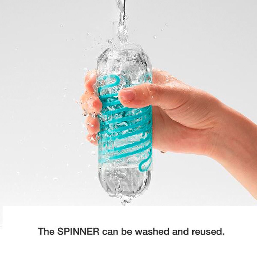 Hand hält transparentes, längliches Produkt mit blauem Spiralmuster unter fließendem Wasser.