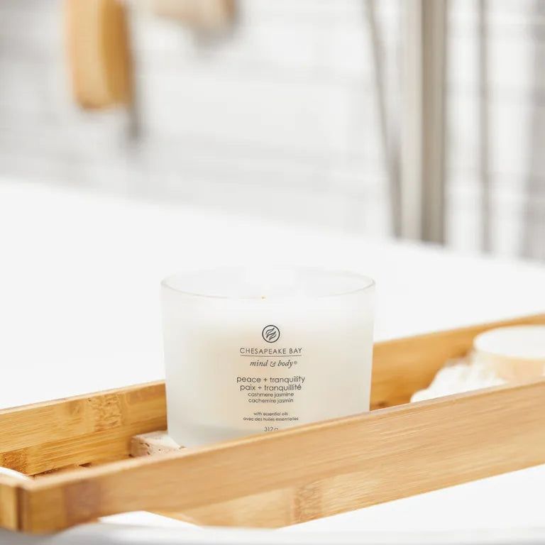 Weißes Glas mit Aufschrift auf einem Bambus-Tablett. Text: Chesapeake Bay, mind & body, peace + tranquility, Paix + tranquillité.
