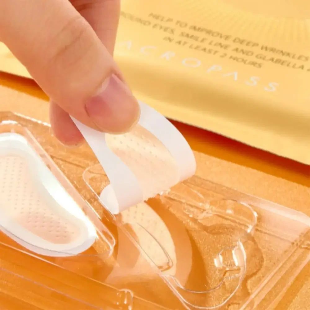 Hand, die einen Retinol-Mikrokegel-Pflaster von der Schutzfolie abzieht. Der Pflaster ist transparent.