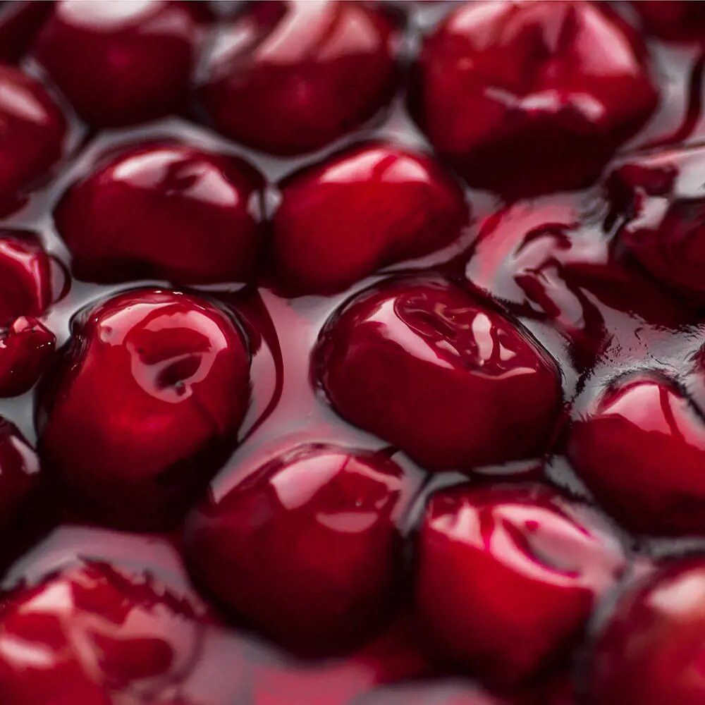 Nahaufnahme von Kirschen in Flüssigkeit. Dunkelrote Kirschen, glänzend, in einer Flüssigkeit. Mehrere Kirschen sichtbar.