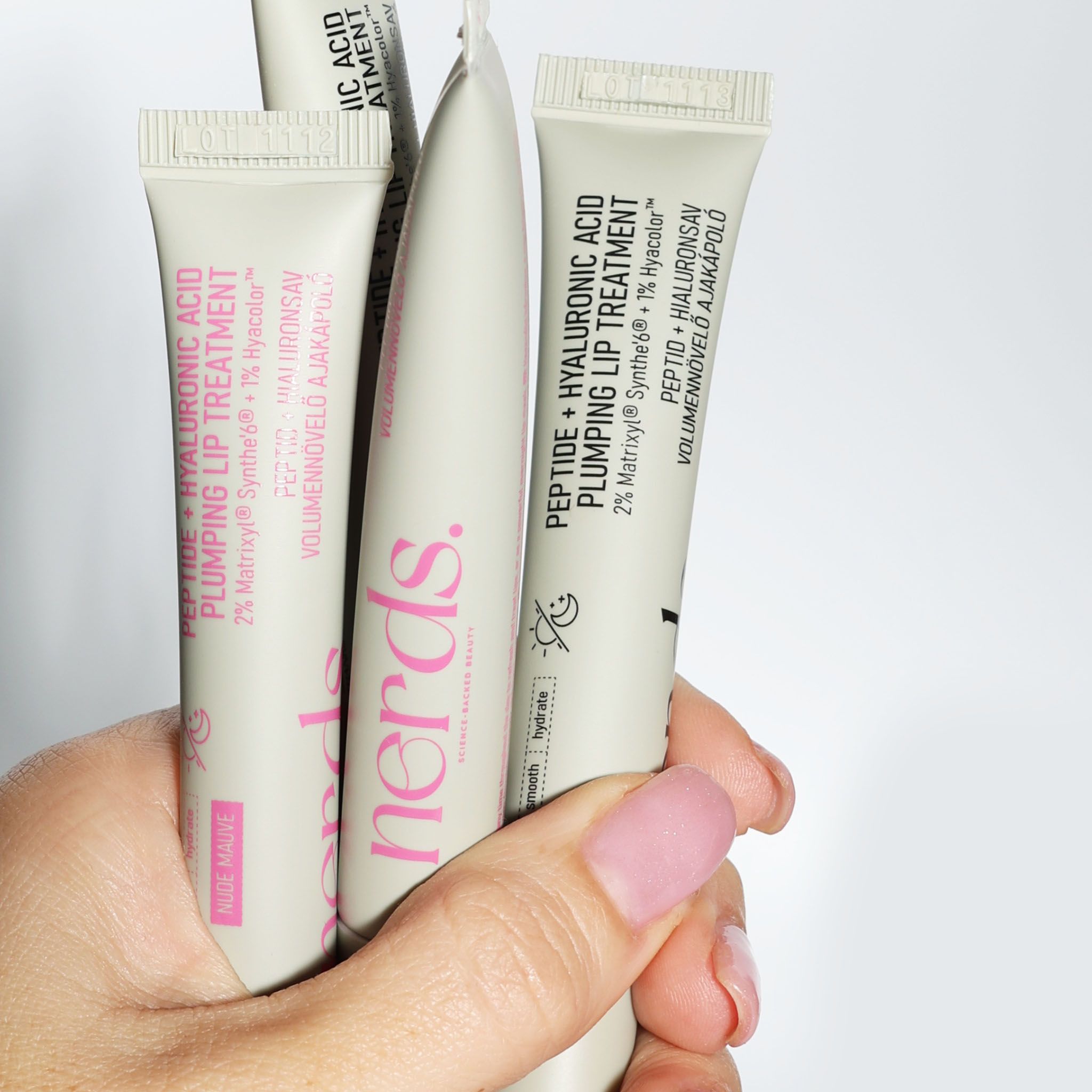 Hand hält mehrere Tuben Lippenpflegeprodukt.