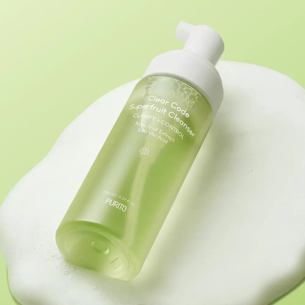 Transparente Flasche mit weißem Pumpspender auf Schaum. Beschriftung: Clear Code Superfruit Cleanser. PURITO-Logo.