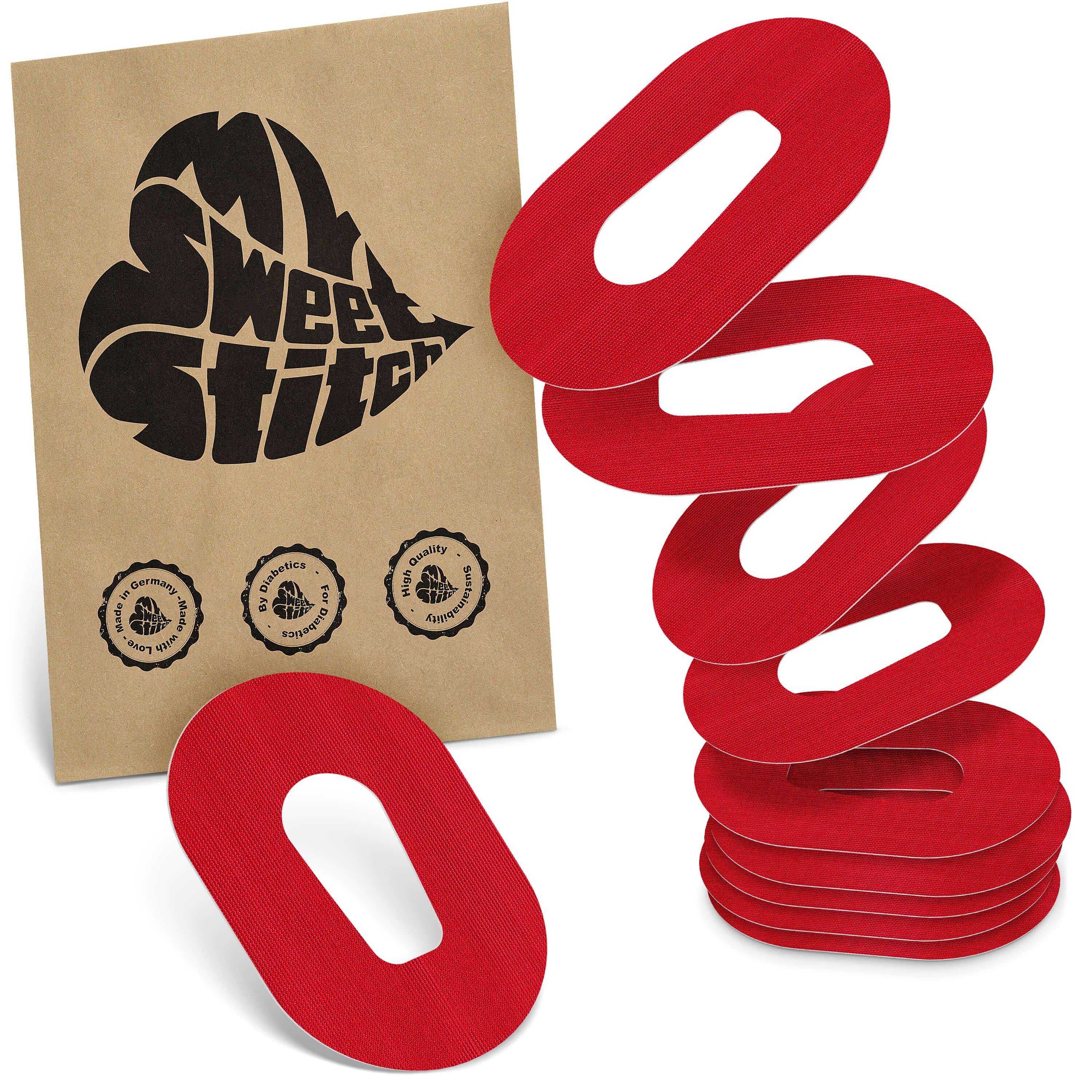 Rote Pflaster mit ovaler Aussparung, gestapelt. Daneben eine braune Papiertüte mit schwarzem Herz-Logo und Siegeln.