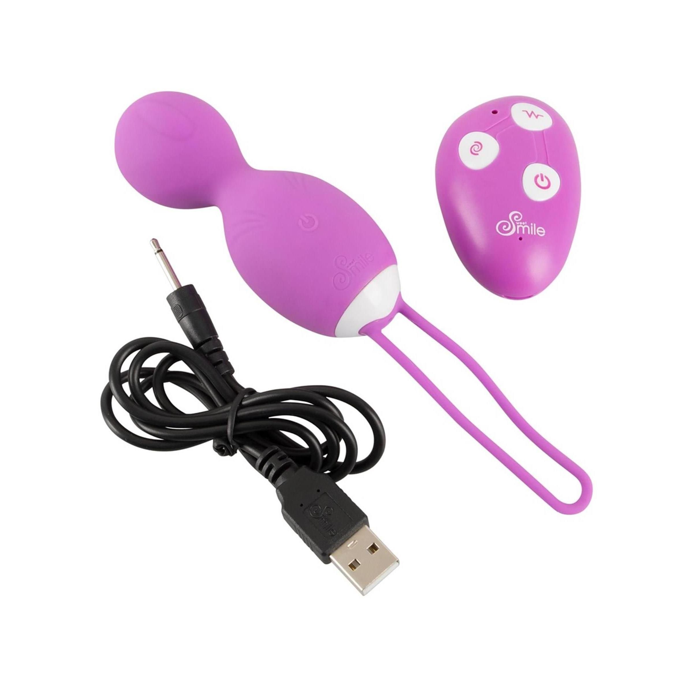 Lila Love Balls mit weißem Akzent und Schlaufe. Fernbedienung und Ladekabel daneben.