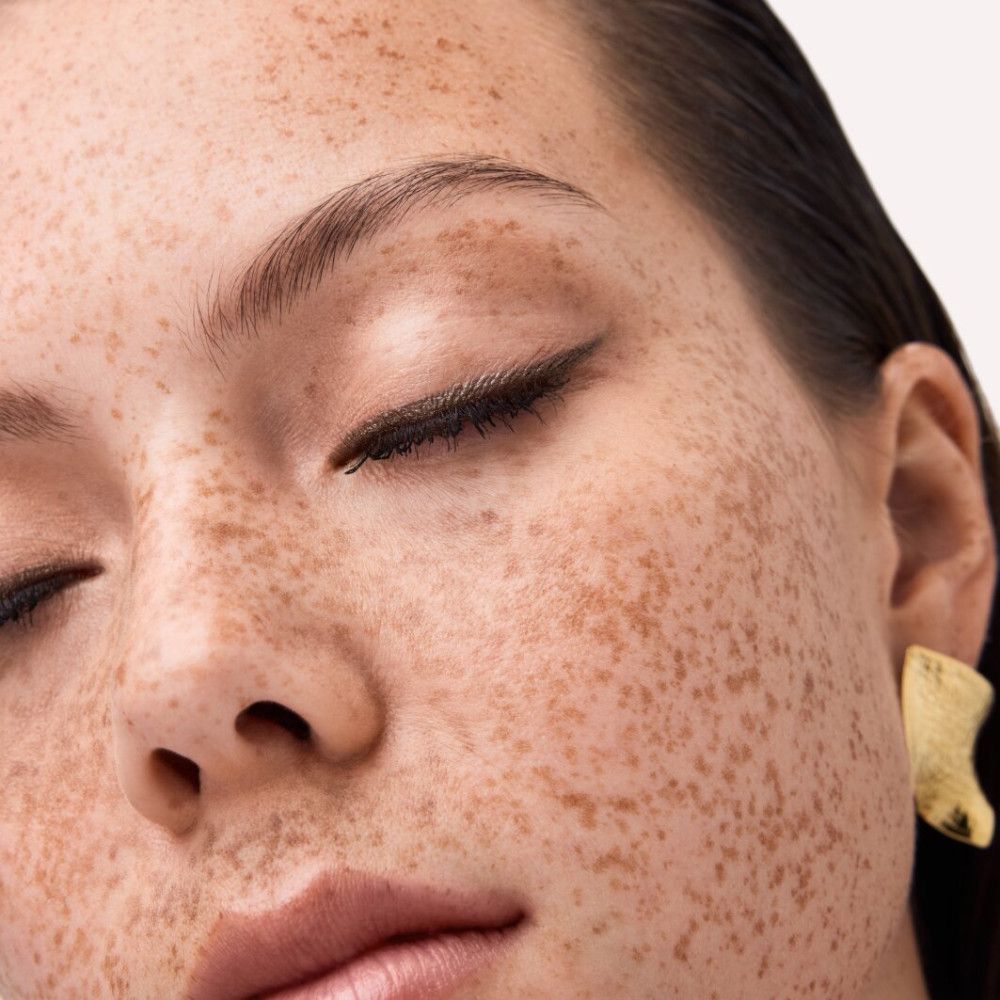 Nahaufnahme eines Gesichts mit Sommersprossen. Geschlossene Augen, Lidstrich.
