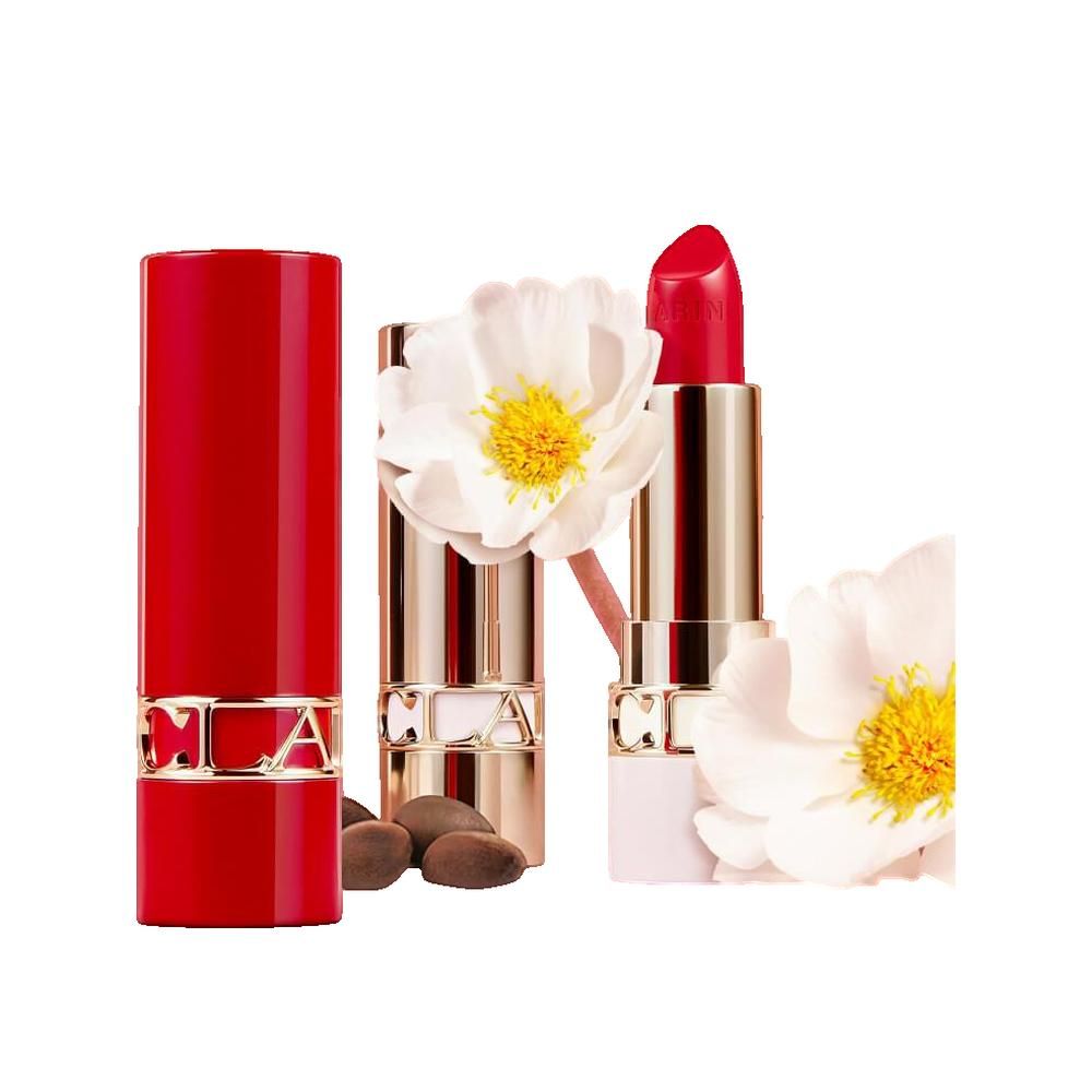 Roter Lippenstift und goldfarbene Hülse. Daneben Blüten und Samen. Markenname sichtbar.