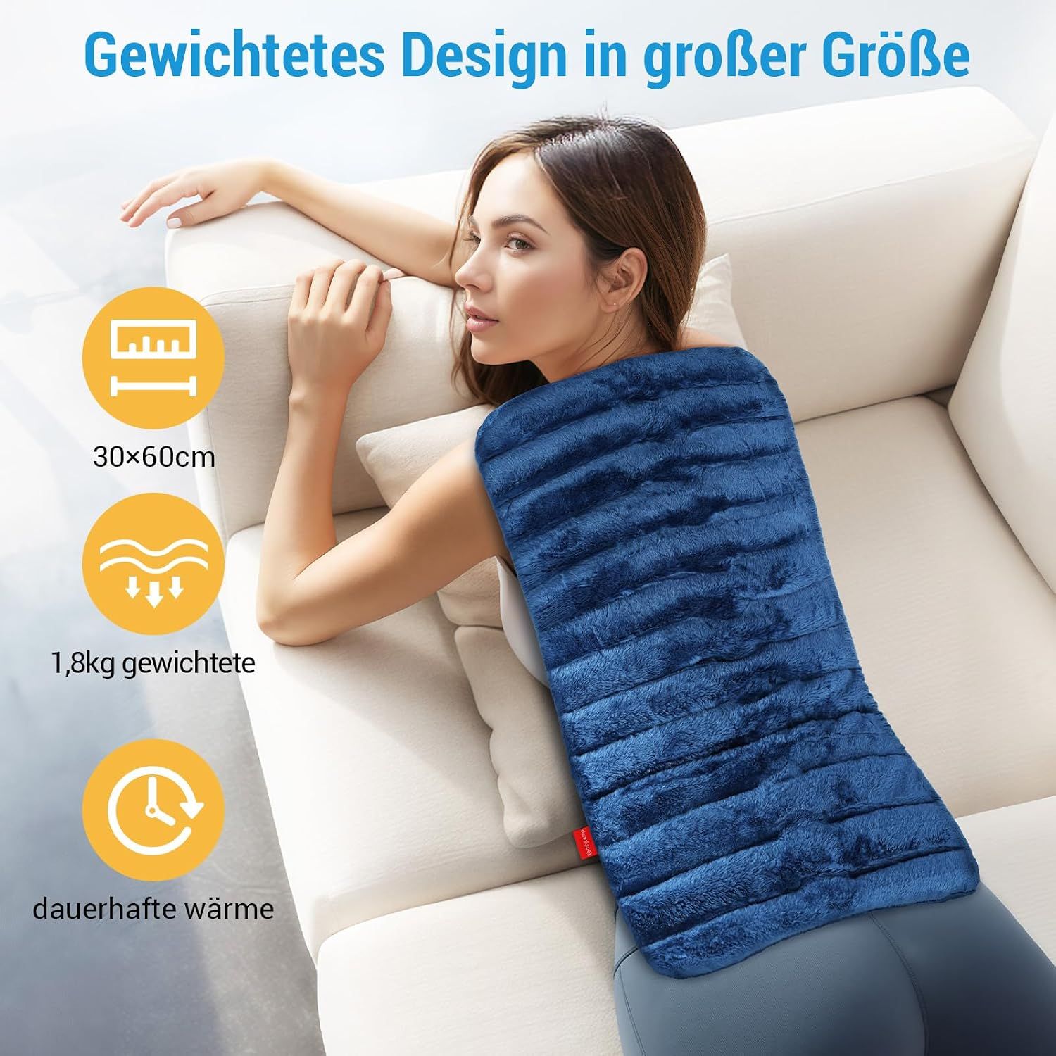 Eine Frau liegt auf einer Couch mit einer blauen, gewichteten Heizdecke (30x60cm, 1.8kg) für langanhaltende Wärme.