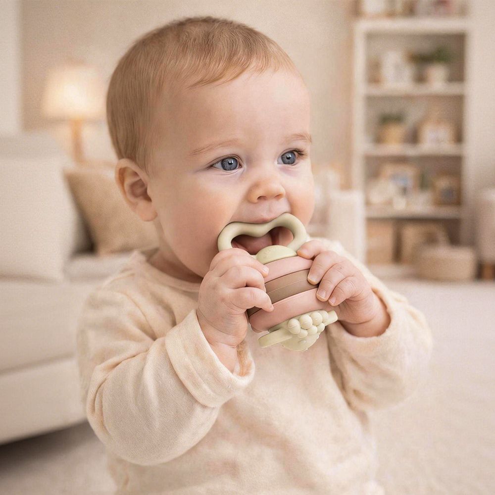 Ein Baby kaut auf einem Beißring in Schaf-Form.