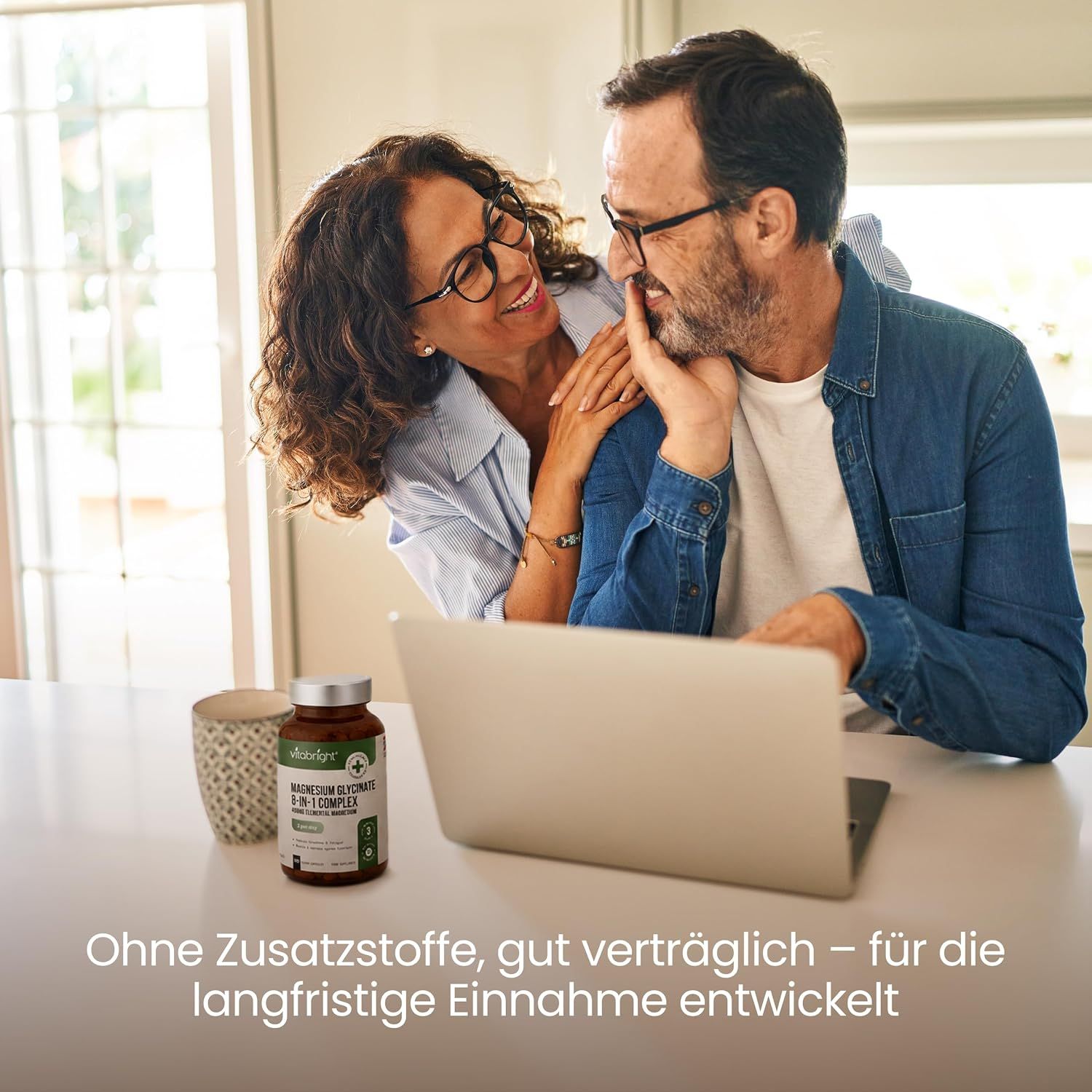 Paar schaut auf Laptop, eine Flasche Nahrungsergänzungsmittel steht daneben.