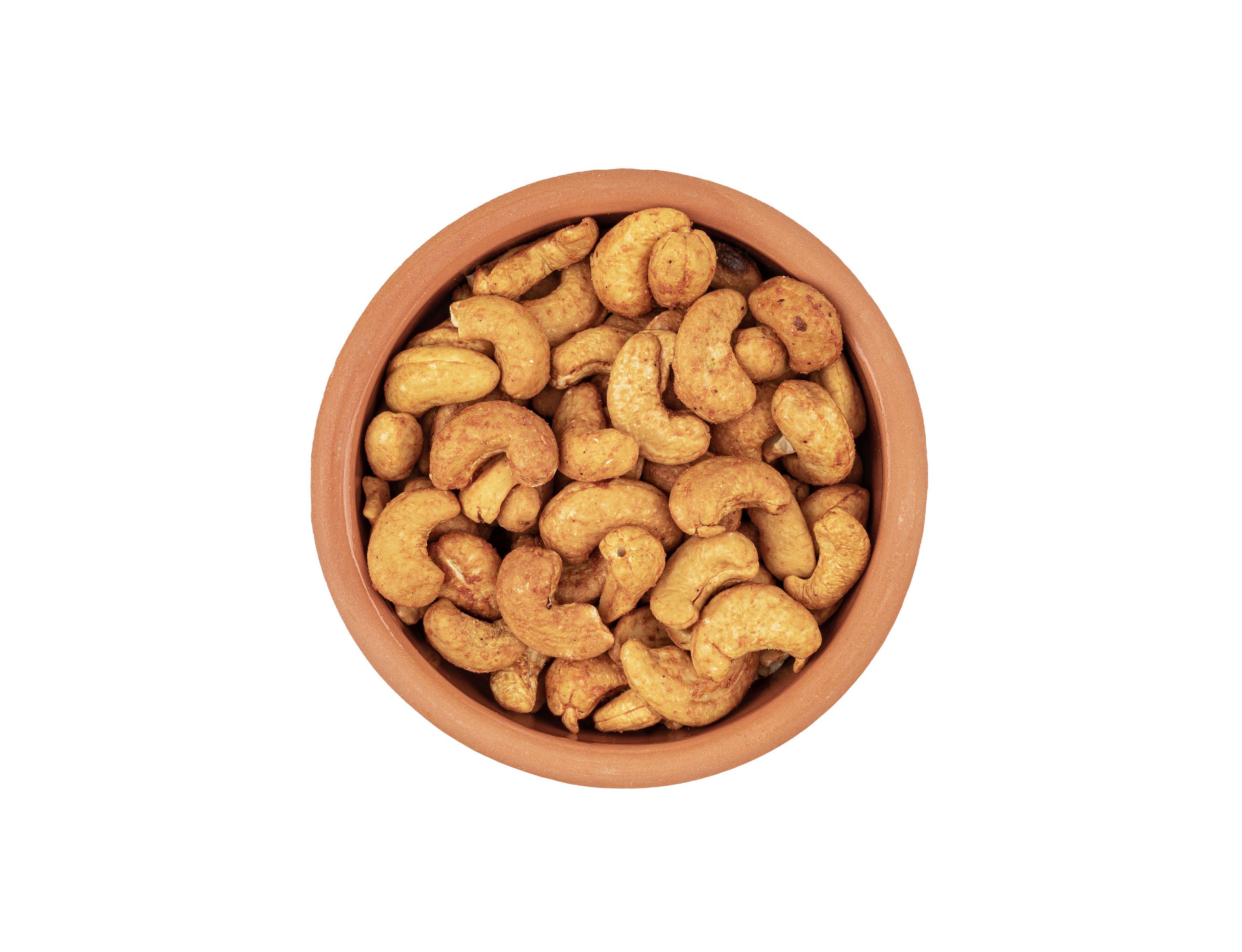 Geröstete Cashewkerne in einer braunen Schale. Draufsicht, isoliert auf weißem Hintergrund.