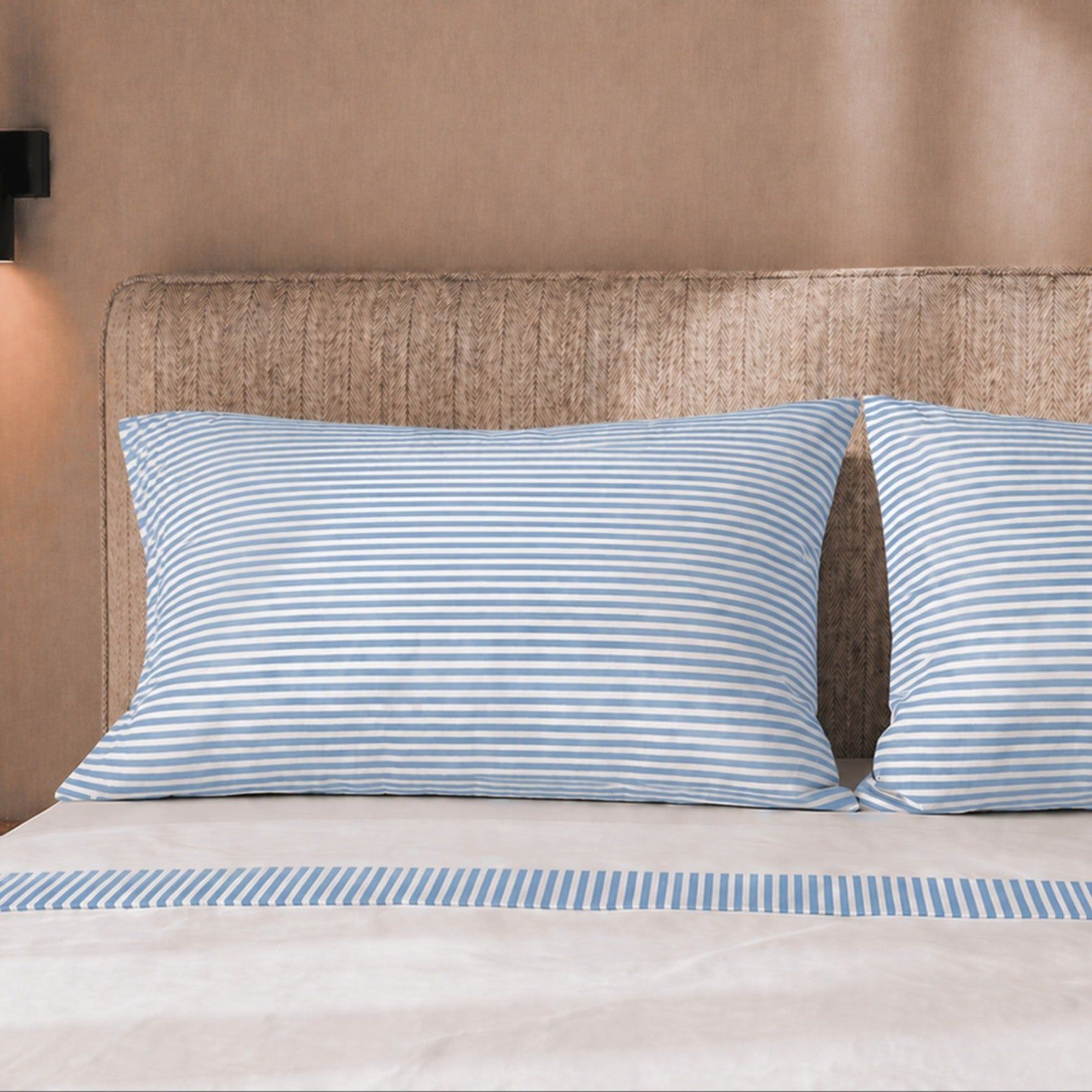 Zwei gestreifte Kissenbezüge auf einem Bett mit gestreiftem Bettbezug.