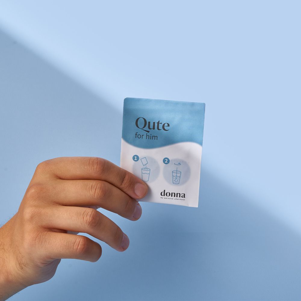 Hand hält einen blauen Beutel mit Produktnamen und Logo. Aufschrift: Qute for him, donna. Blaues Hintergrund.