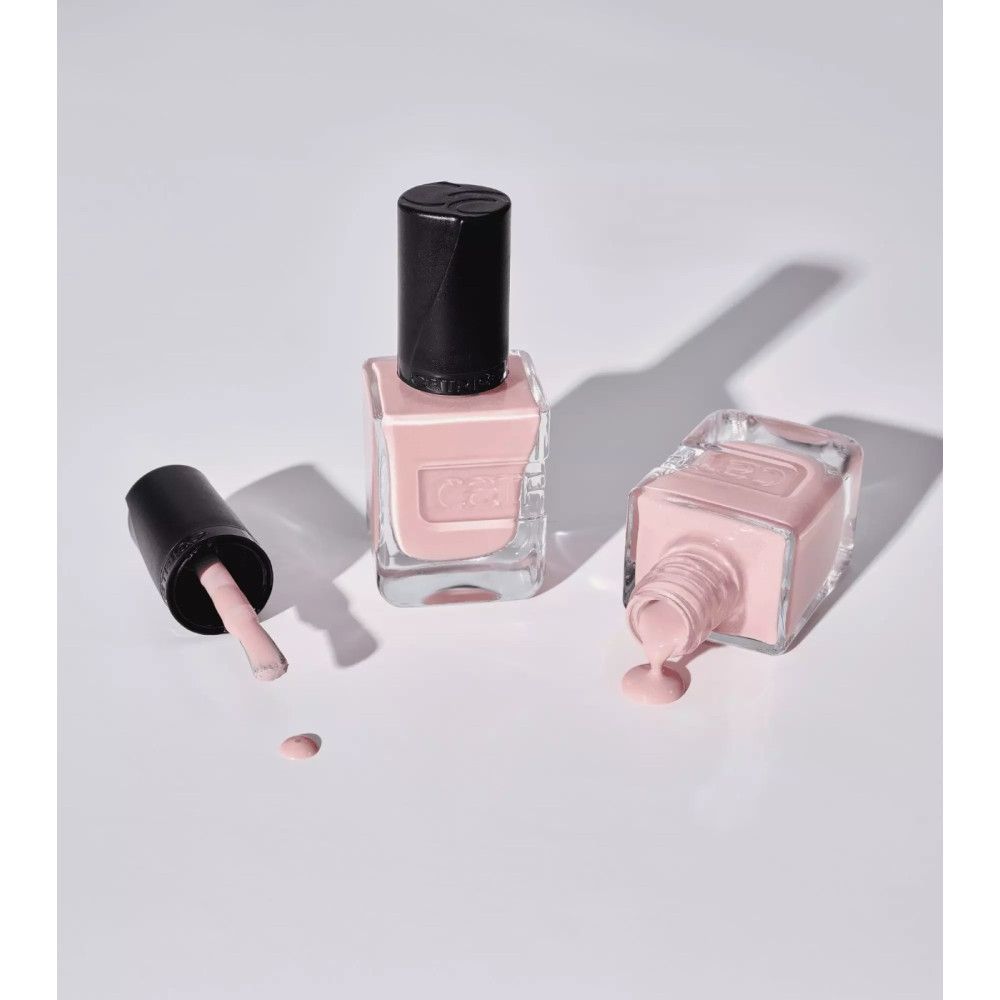 Drei Nagellackflaschen, eine mit geöffnetem Deckel, eine umgekippt. Rosa Farbton. Marke Catrice.