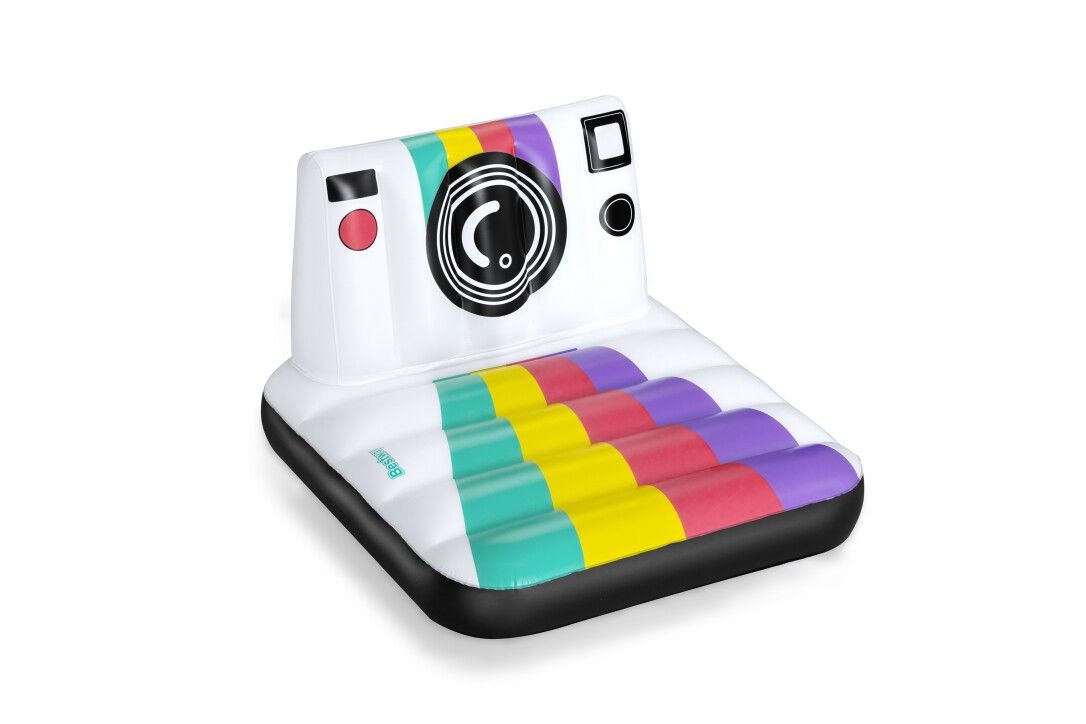 Aufblasbare Luftmatratze in Kameraform. Weiße Basis mit bunten Streifen. Schwarzer Rand und Kamera-Details.
