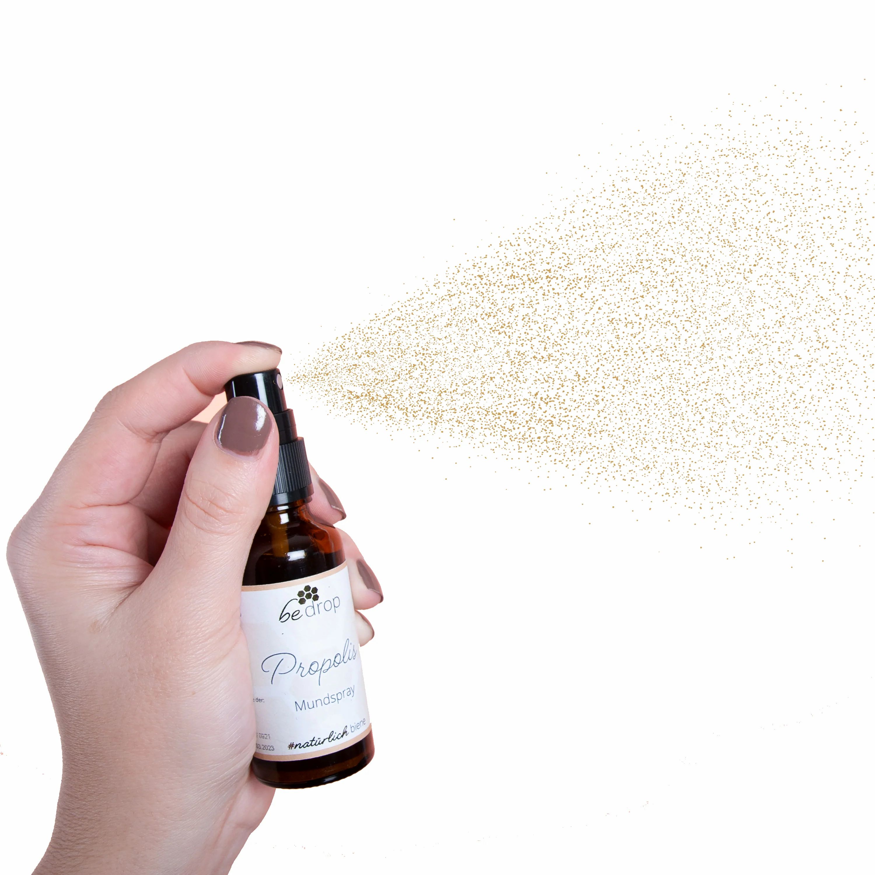 Hand hält braune Flasche mit Sprühkopf. Sprühnebel sichtbar. Aufschrift: bedrop Propolis Mundspray.