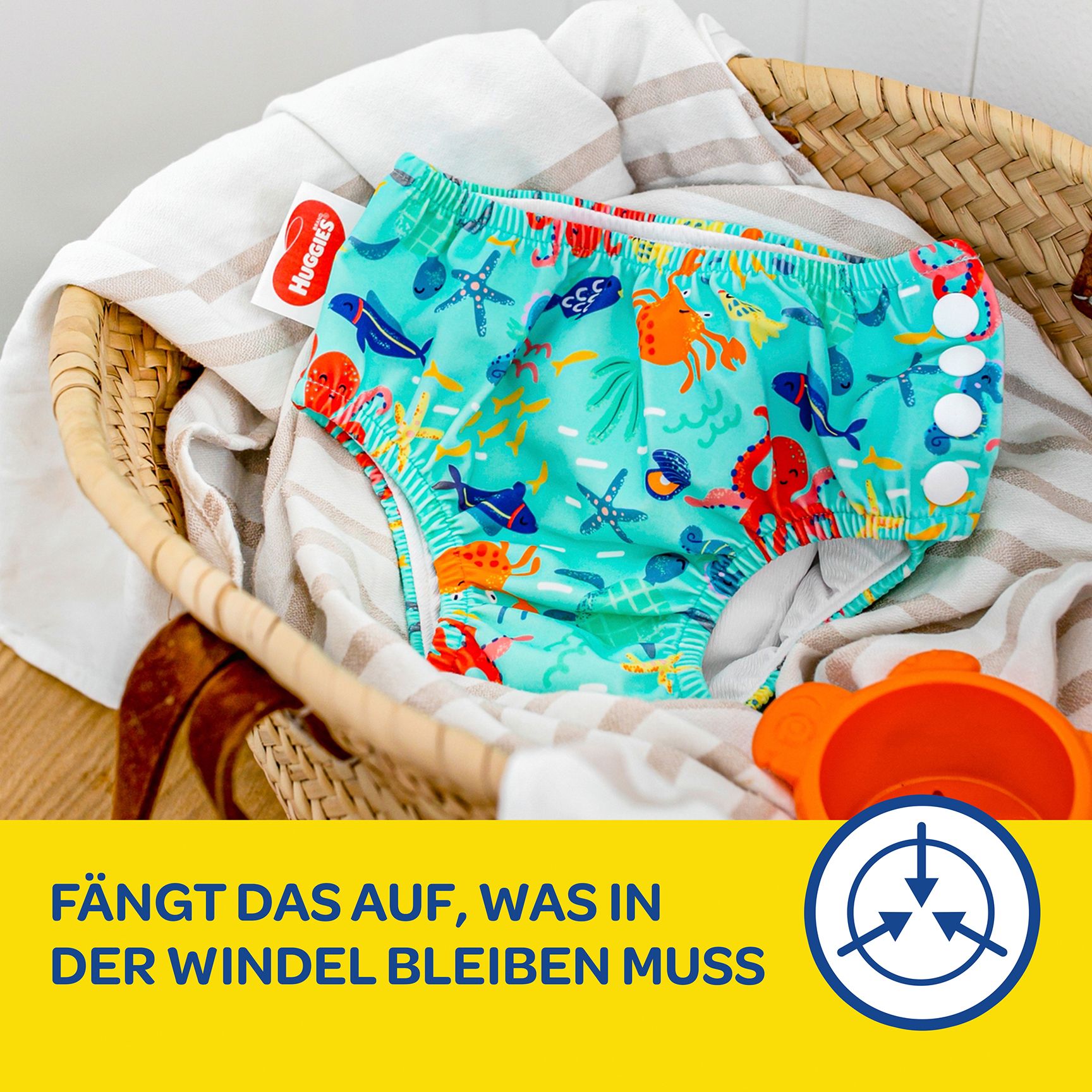 Schwimmwindel mit Meeresmotiven in einem Korb. Marke Huggies. Text: Fängt das auf, was in der Windel bleiben muss.
