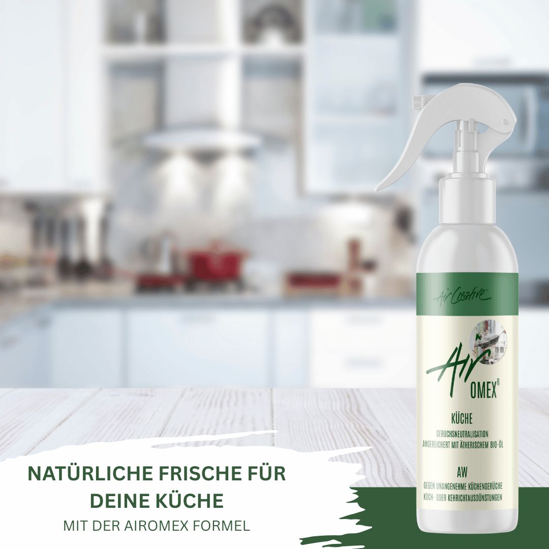 Sprühflasche mit weißem Sprühkopf. Aufschrift: Air Creative, Airomex Küche. Auf einem Holztisch, Hintergrund: Küche.