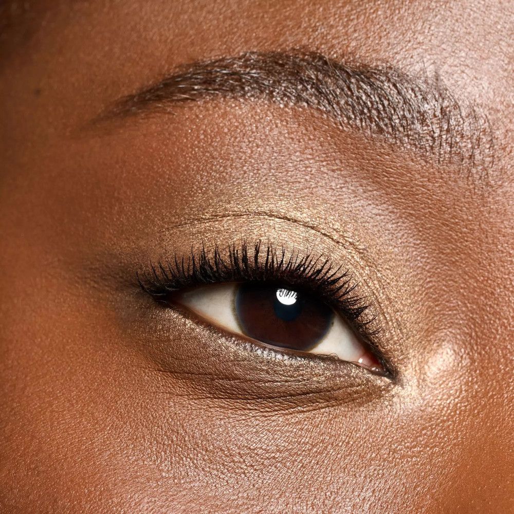 Nahaufnahme eines Auges mit braunem Lidschatten. Wimpern sind betont.