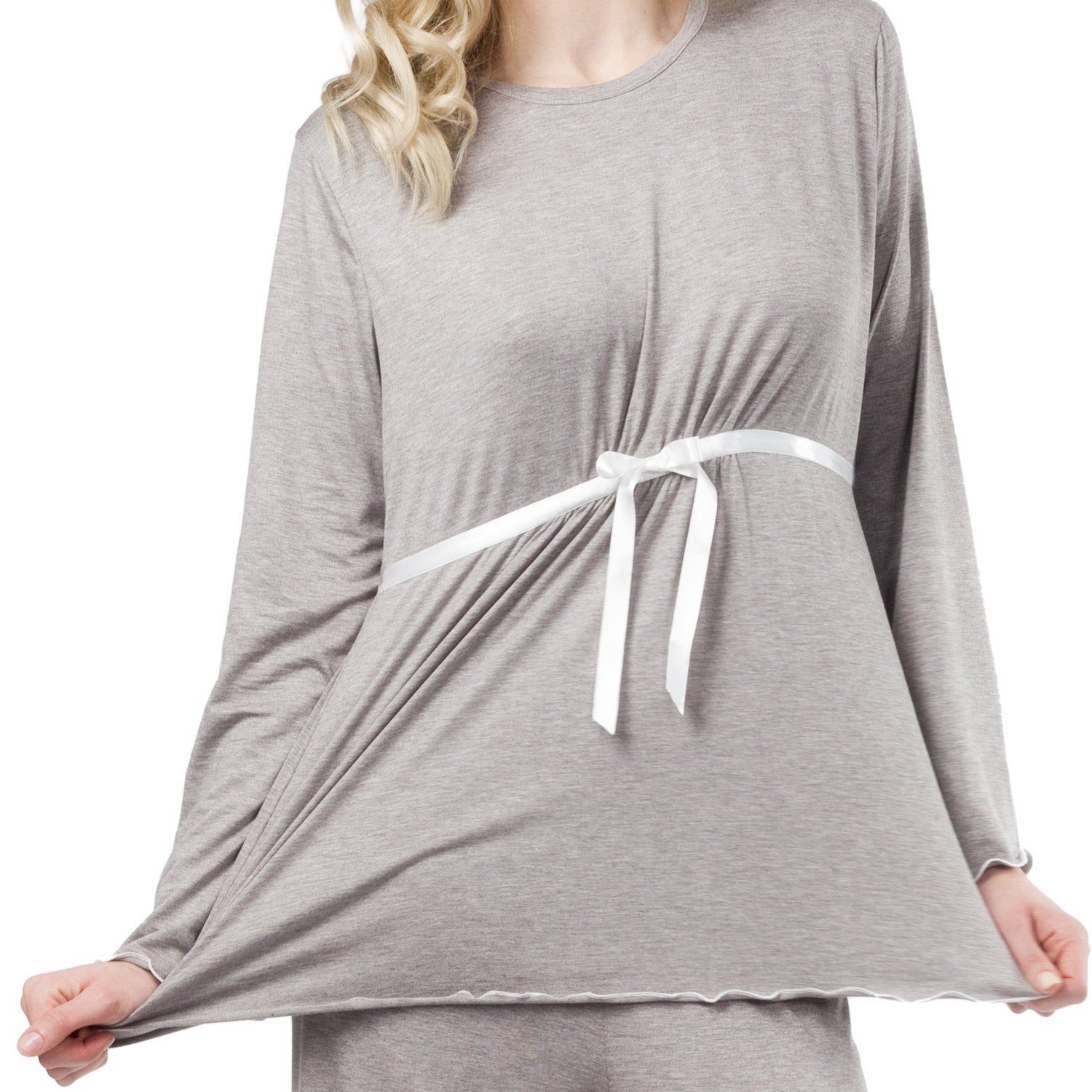 Graues Schwangerschaftspyjama-Oberteil. Langärmlig mit weißem Bindeband. Frau hält Stoff auseinander. Weißer Saum.