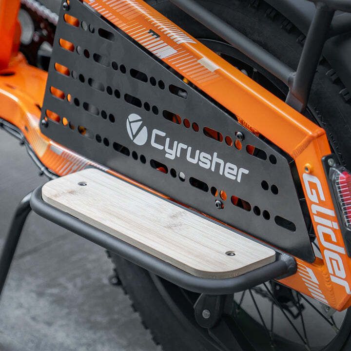 Orangefarbenes Fahrrad mit schwarzem Gepäckträger und Holztrittbrett. Cyrusher-Logo sichtbar.