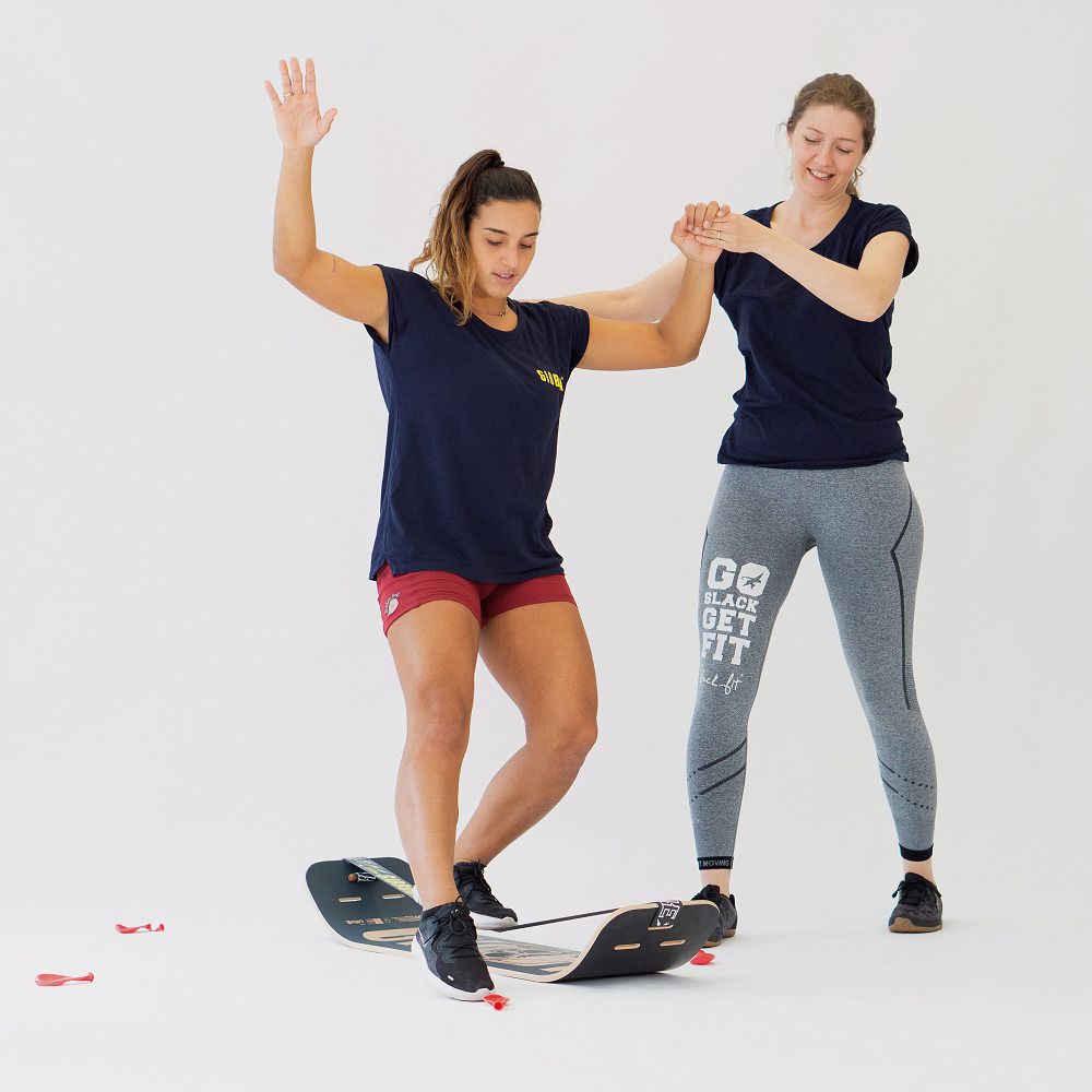Person balanciert auf GIBOARD SET - CAESAR JIB, Trainer gibt Halt, kleine rote Elemente am Boden.