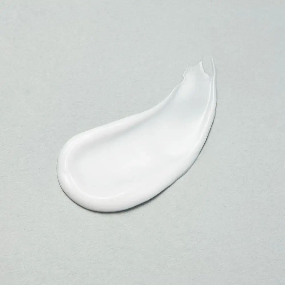 Klecks weiße Lotion auf grauem Hintergrund. Glatte Textur, leicht glänzend.