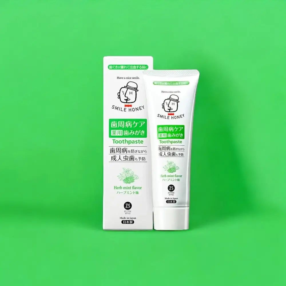 Zahnpasta-Tube und Verpackung, weiß, mit grünen und schwarzen Schriftzügen. Aufschrift: SMILE HONEY, Toothpaste, Herb mint flavor.