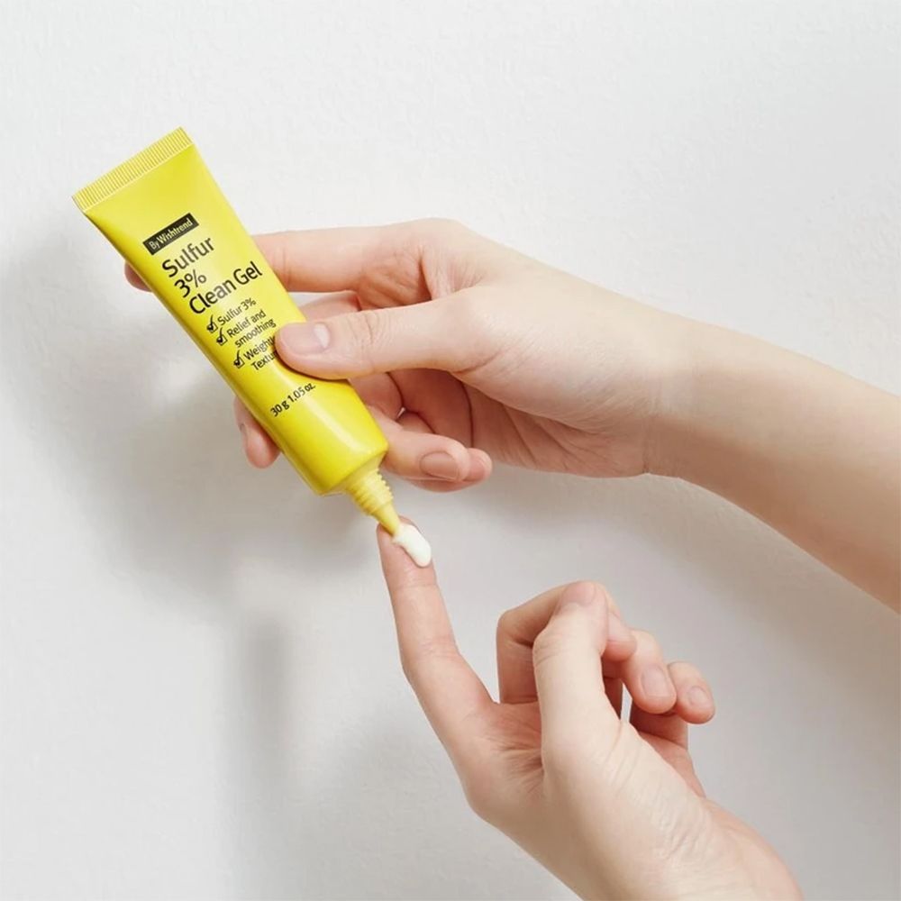 Gel-Tube, gelb, wird von Händen gehalten. Gel wird auf einen Finger aufgetragen. Aufschrift Sulfur 3% Clean Gel.