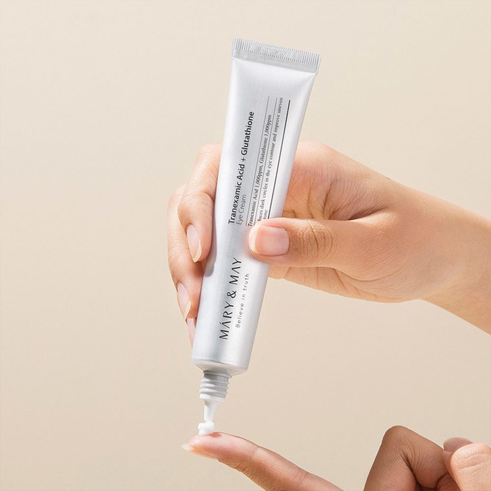 Hand hält Tube. Creme wird auf Finger aufgetragen. MARY & MAY Logo und Produkttext sichtbar.