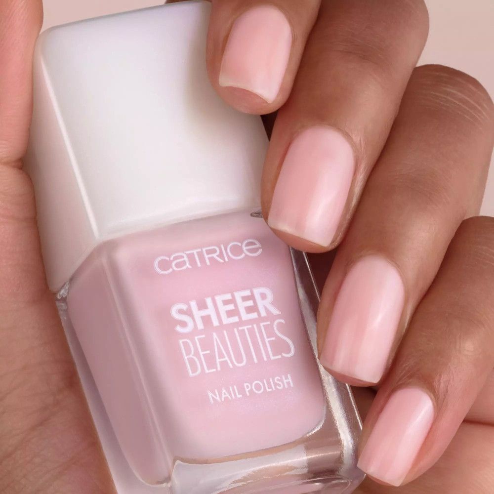 Hand mit lackierten Nägeln und Nagellackflasche. Aufschrift: Catrice Sheer Beauties Nail Polish.