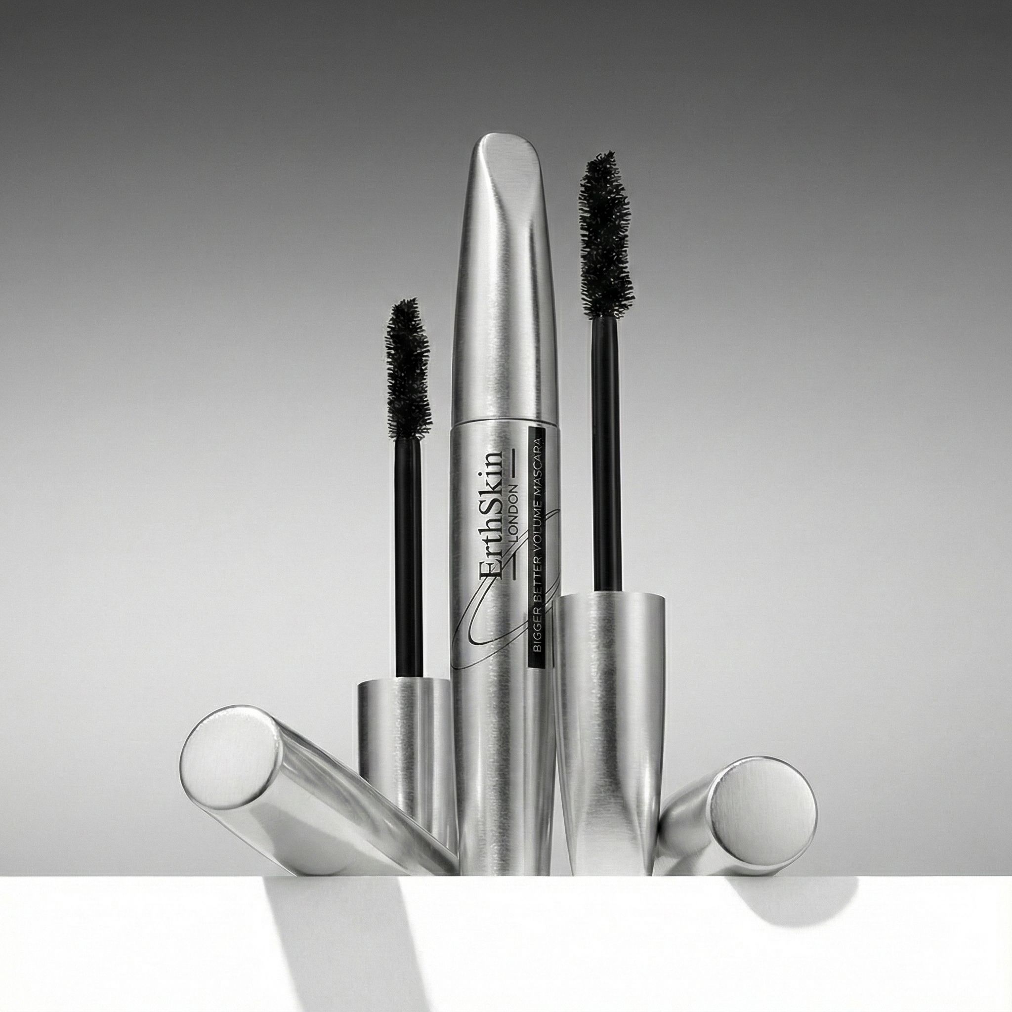 Drei silberne Mascara-Verpackungen und Applikatoren mit schwarzen Bürsten.