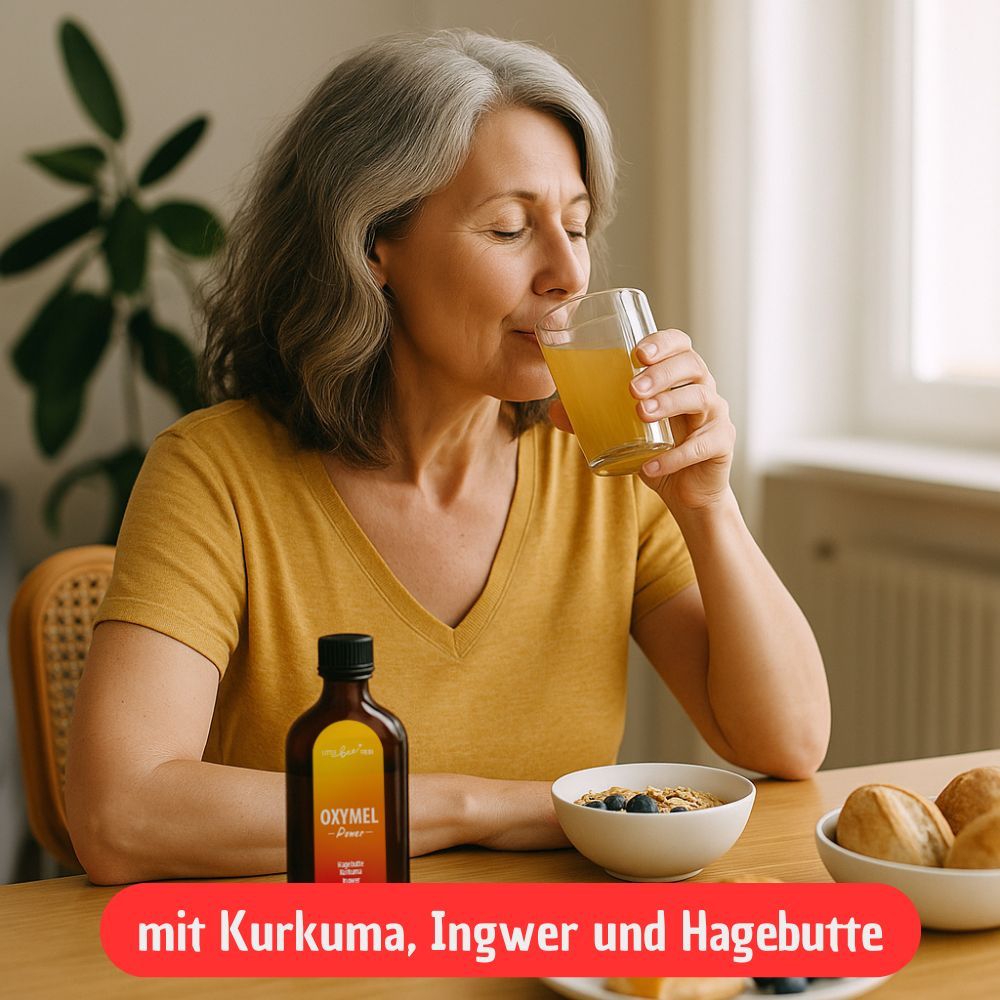 Frau trinkt aus einem Glas. Flasche steht daneben. Text: mit Kurkuma, Ingwer und Hagebutte. Auf dem Tisch: Schüssel mit Müsli und Brot.
