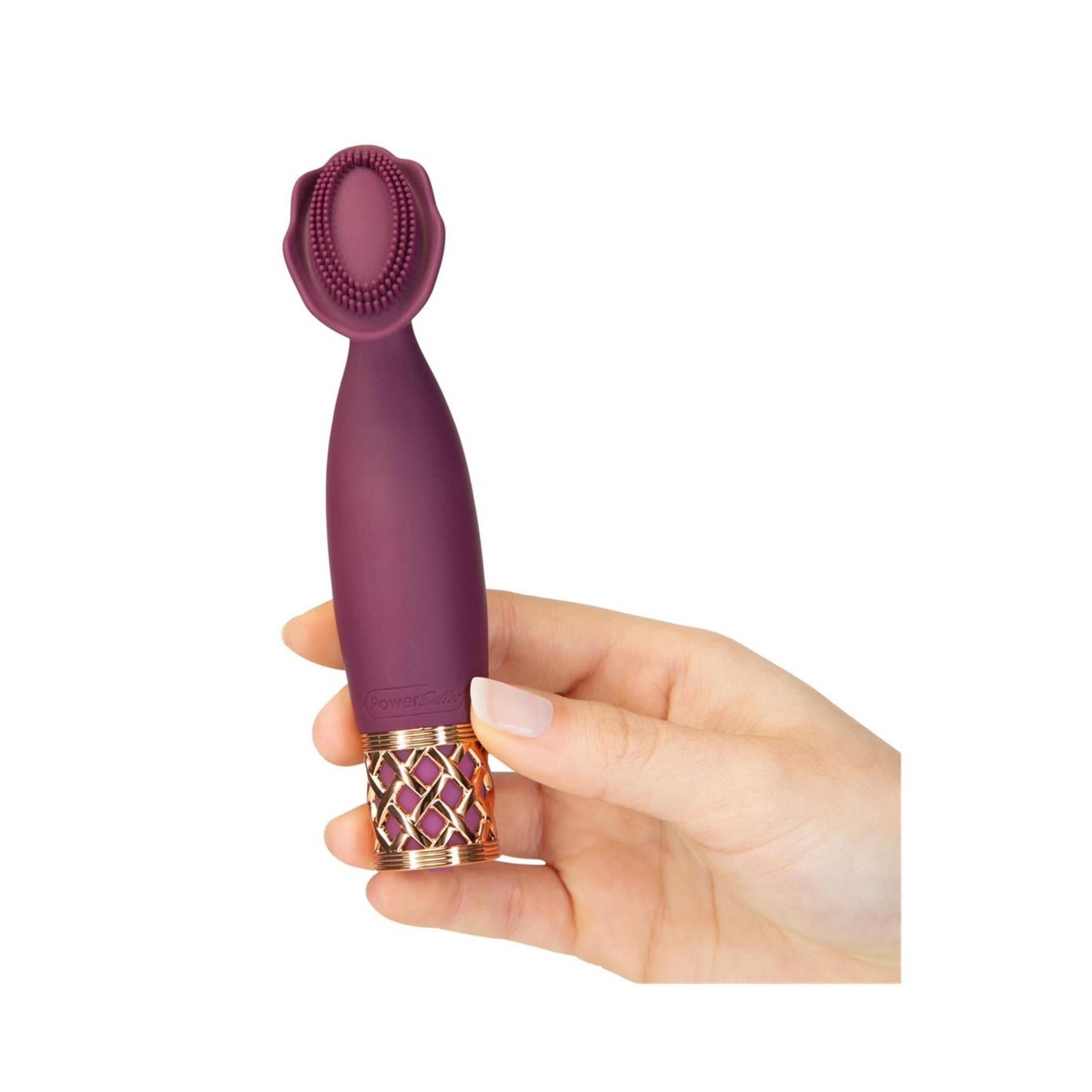 Hand hält einen lila Vibrator. Goldfarbenes Gittermuster am Griff, blütenförmiger Aufsatz.