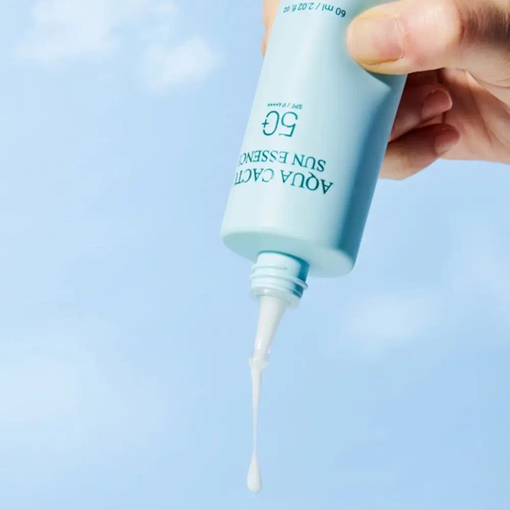 Hellgrüne Flasche mit weißem Applikator. Aufschrift: Aqua Cactus Sun Essence 50. Produkt wird aus der Flasche gedrückt.