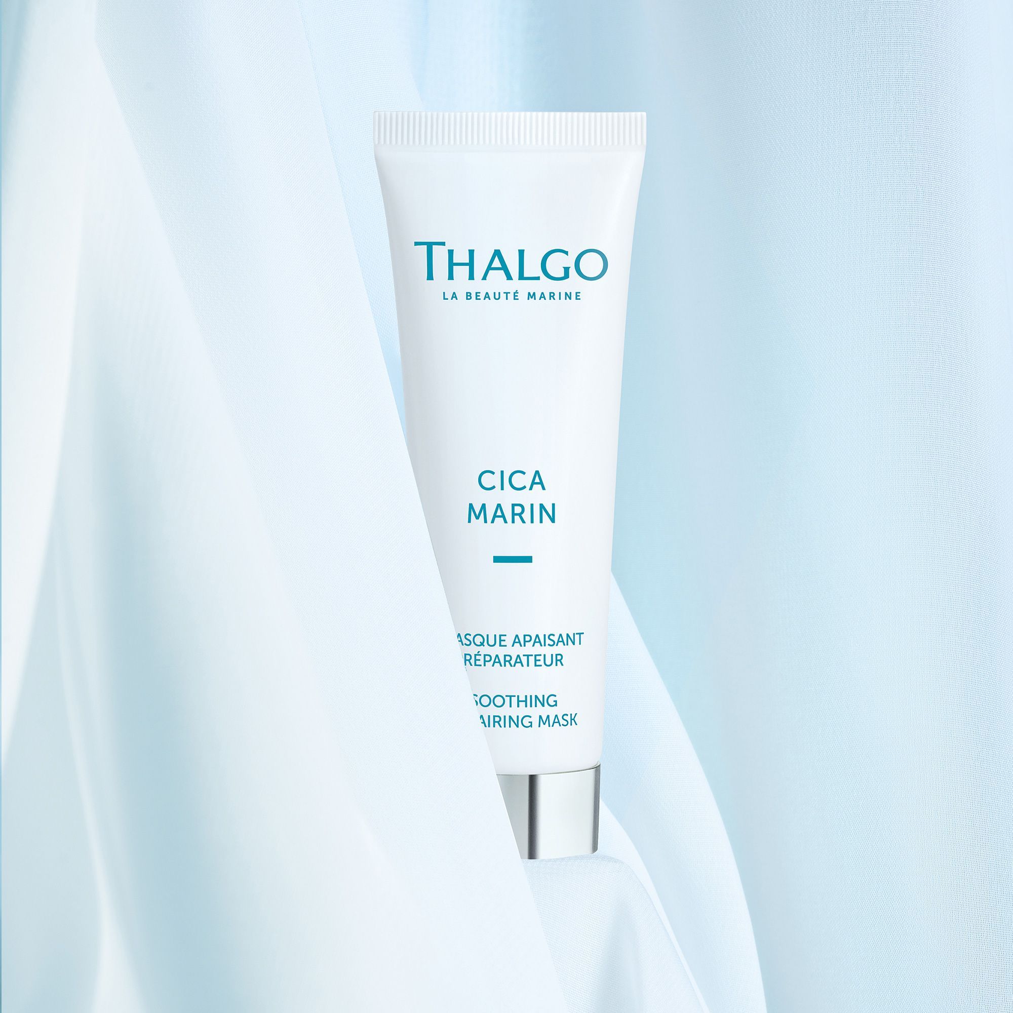 Weiße Tube mit blauem Schriftzug THALGO, CICA MARIN, und Produktbezeichnung. Silberner Schraubverschluss. Auf blauem Stoff drapiert.