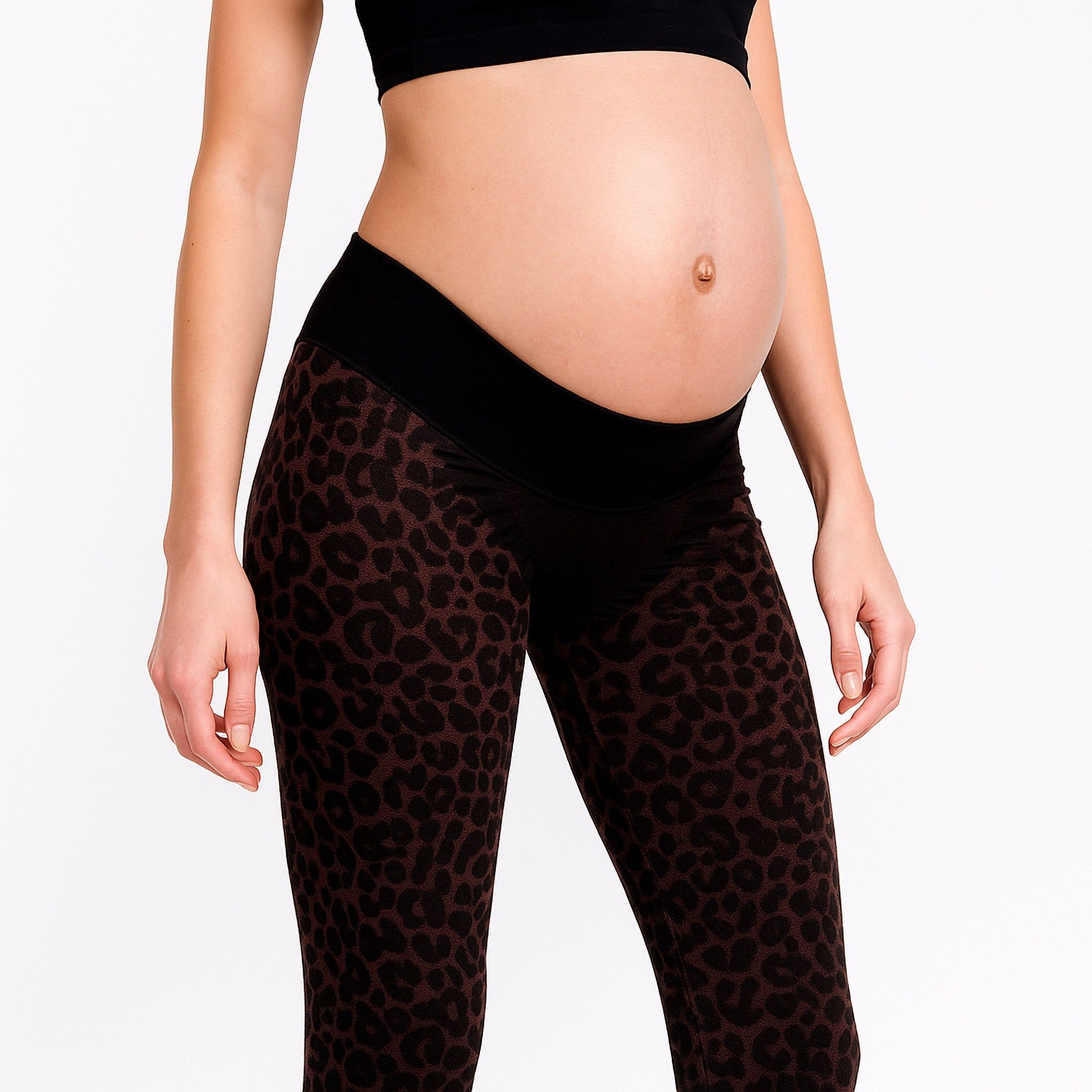 Braune Leggings mit Leopardenmuster und schwarzem Bund. Schwangere Frau trägt Sport-BH.