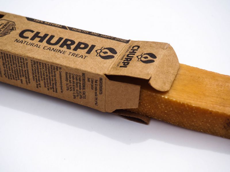 Churpi-Hundesnack in geöffneter Kartonverpackung. Der Snack ist sichtbar. Braune Verpackung mit Produktnamen und Text.